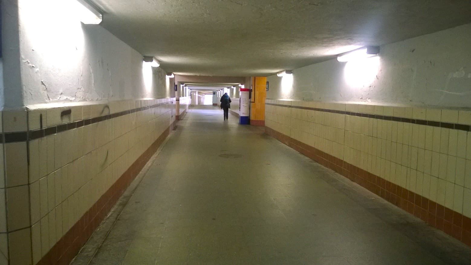 Zu sehen ist der Tunnel des Bahnhofs Flöha vor der Sanierung mit hellgelben Fliesen an den Wänden.