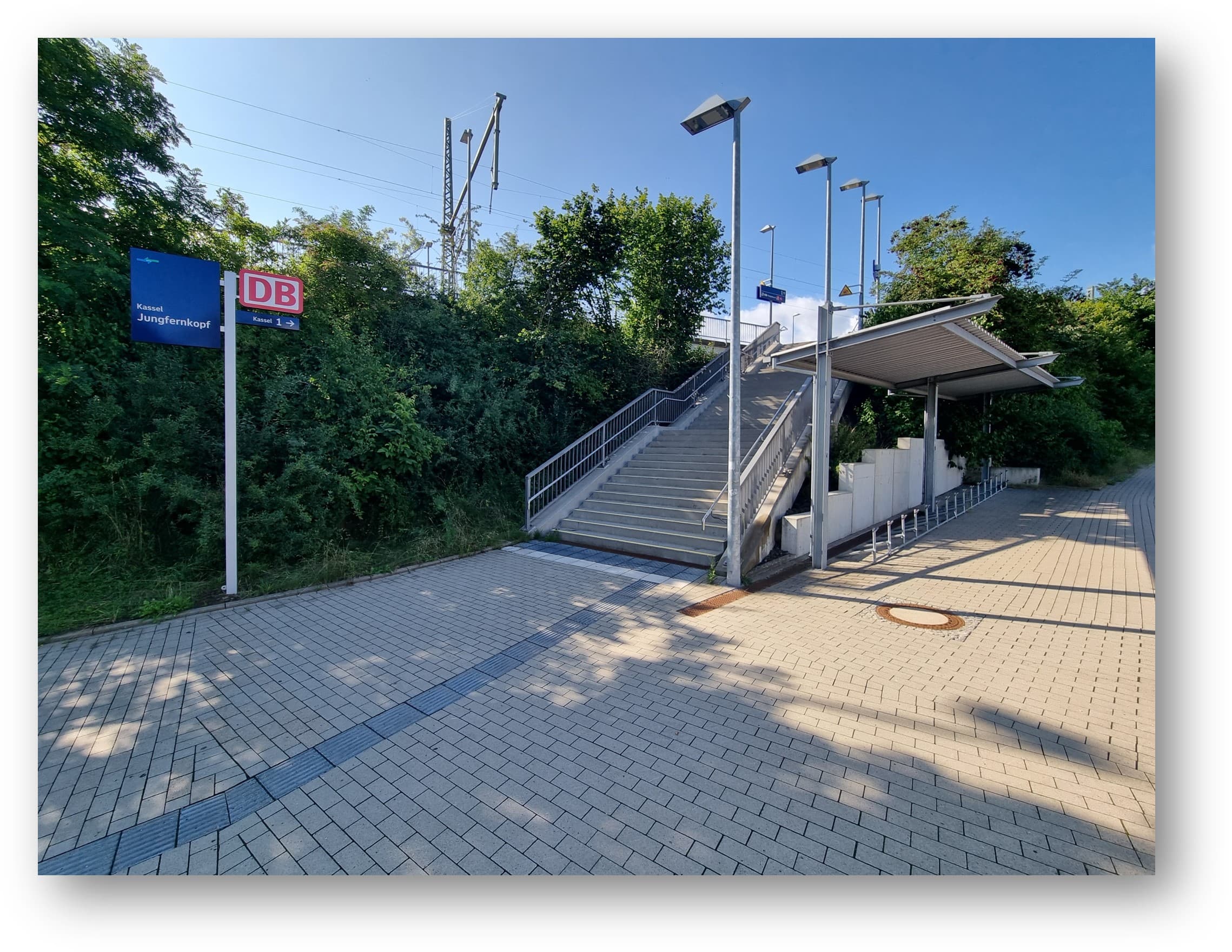 Blick auf die überdachten Fahrradbügel. Daneben befindet sich eine Treppe die zum Bahnsteig führt.
