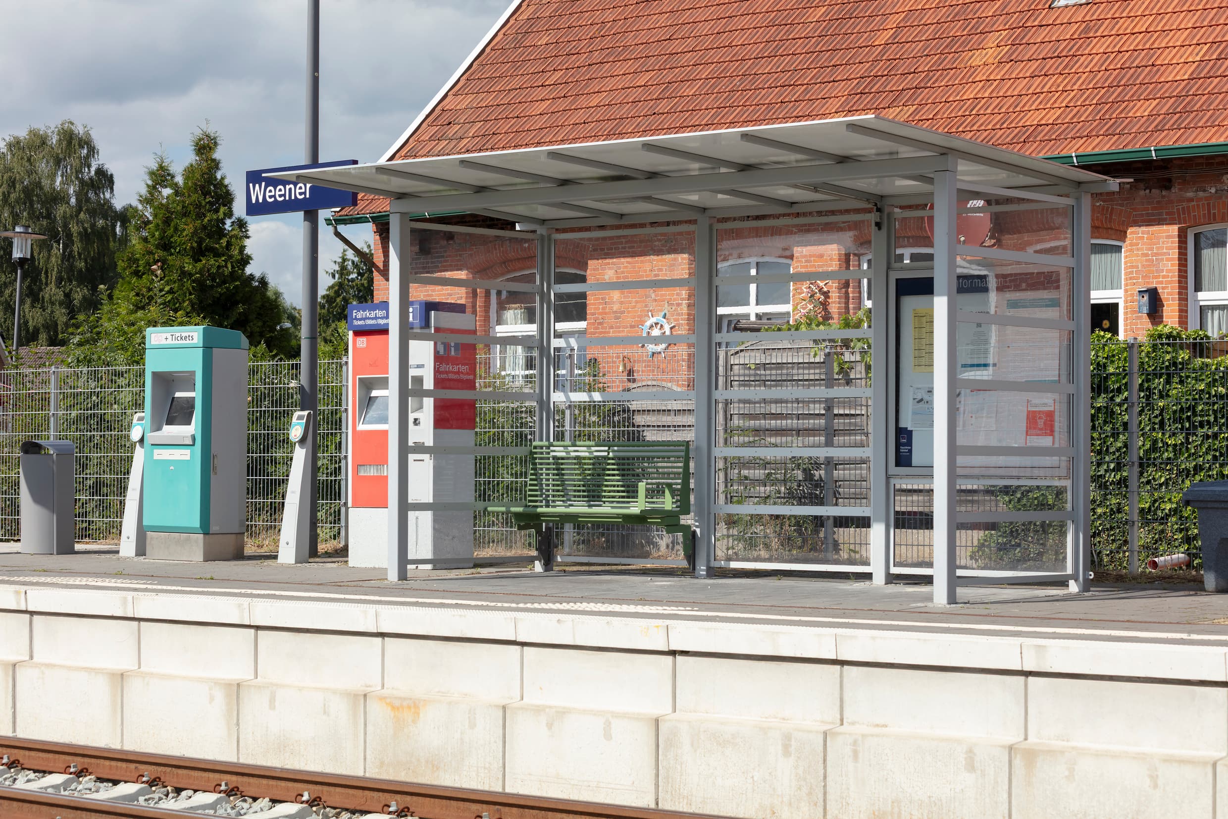Bahnsteig mit einem neuen Wetterschutzhaus mit Calidum Sitzbank, neuer Beschilderung und einer neuen Vitrine.