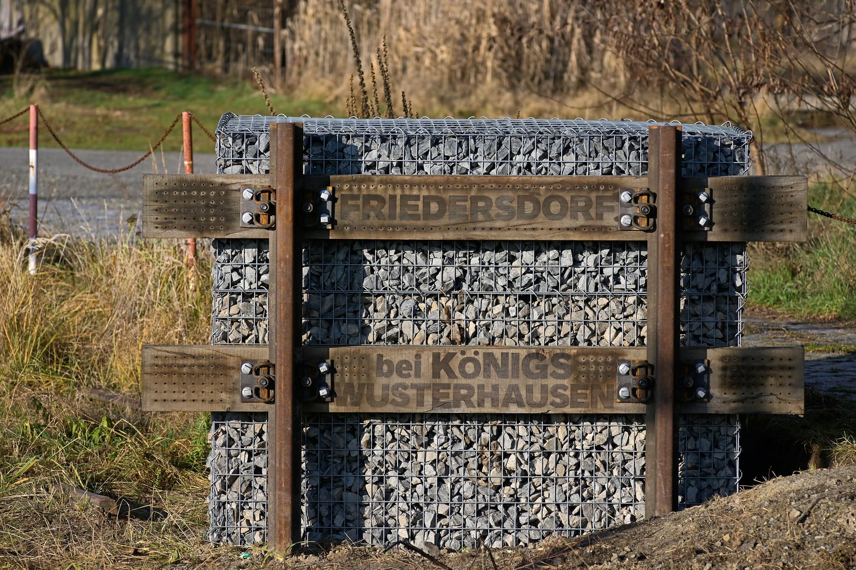 Bahnhofsschild aus Holz und Stein.