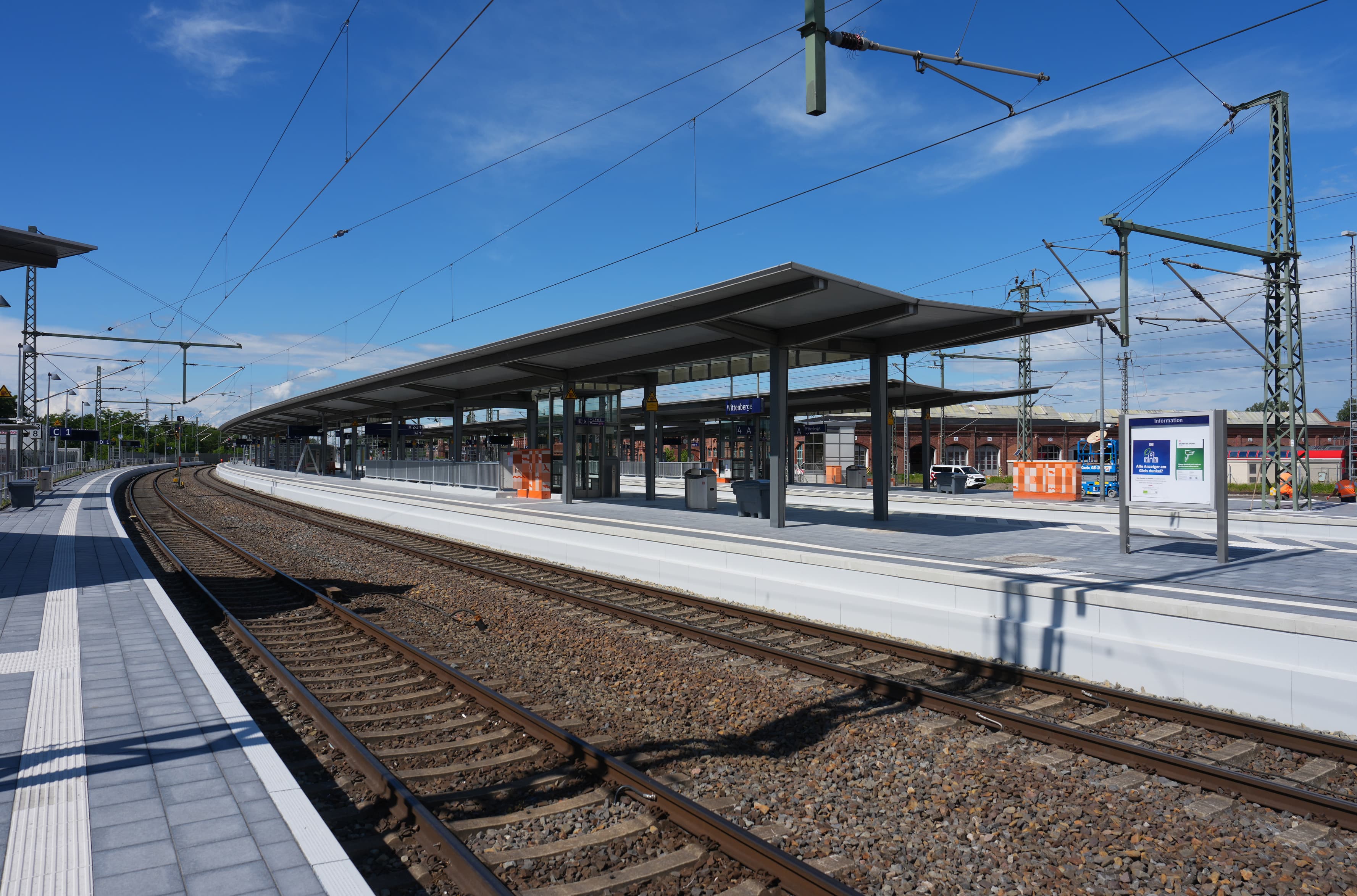 Ein Mittelbahnsteig mit einem Bahnsteigdach an einem Bahnhof.