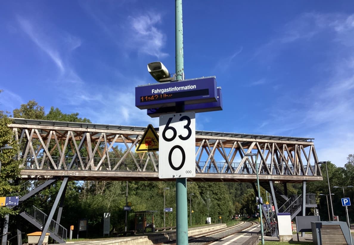 Alte Fahrgastinformation. Im Hintergrund befindet sich eine Metallbrücke.