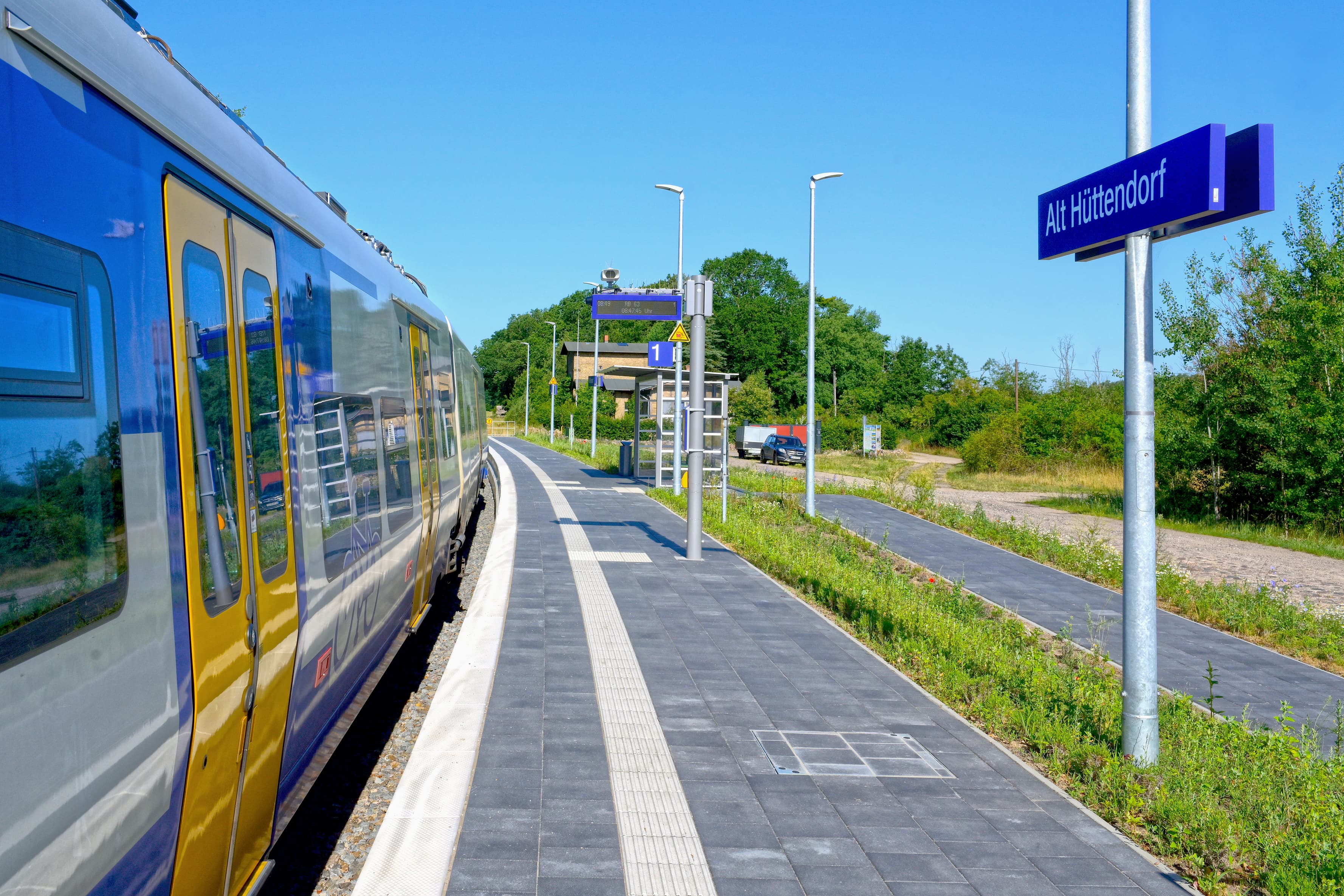 Ein Zug hält am modernen Bahnsteig des Zukunftsbahnhofs Alt Hüttendorf.