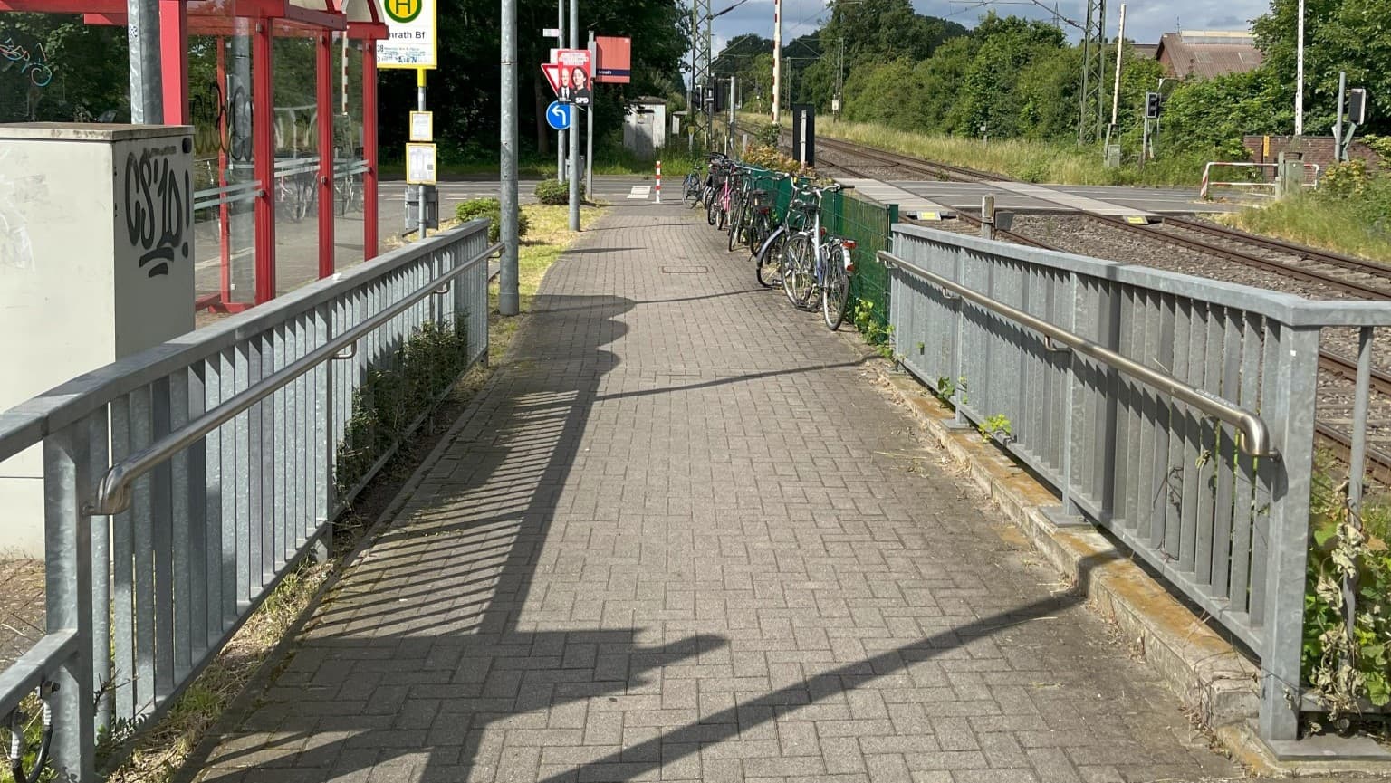 Metallgeländer ohne Anstrich, in der Mitte ein gepflasterter Weg.