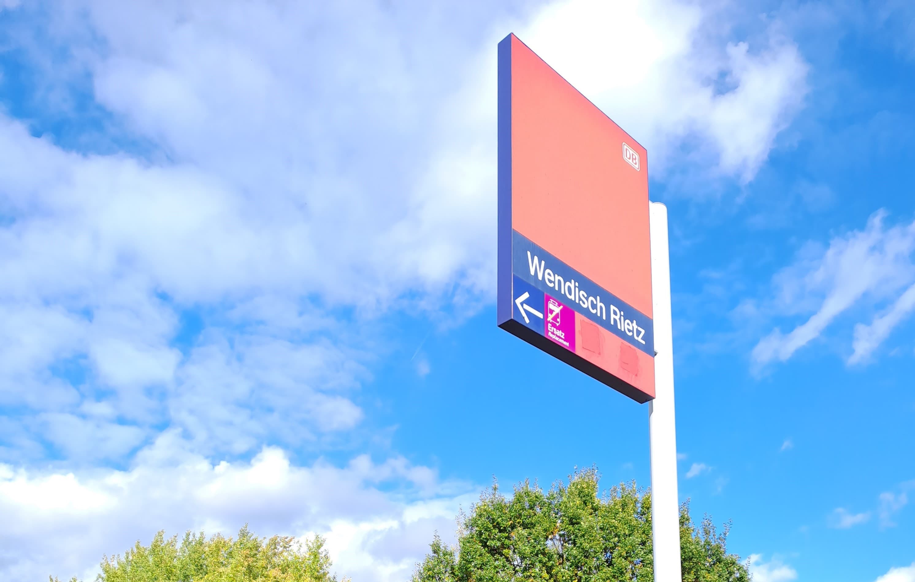 Ein rot-blaues Bahnhofsschild.