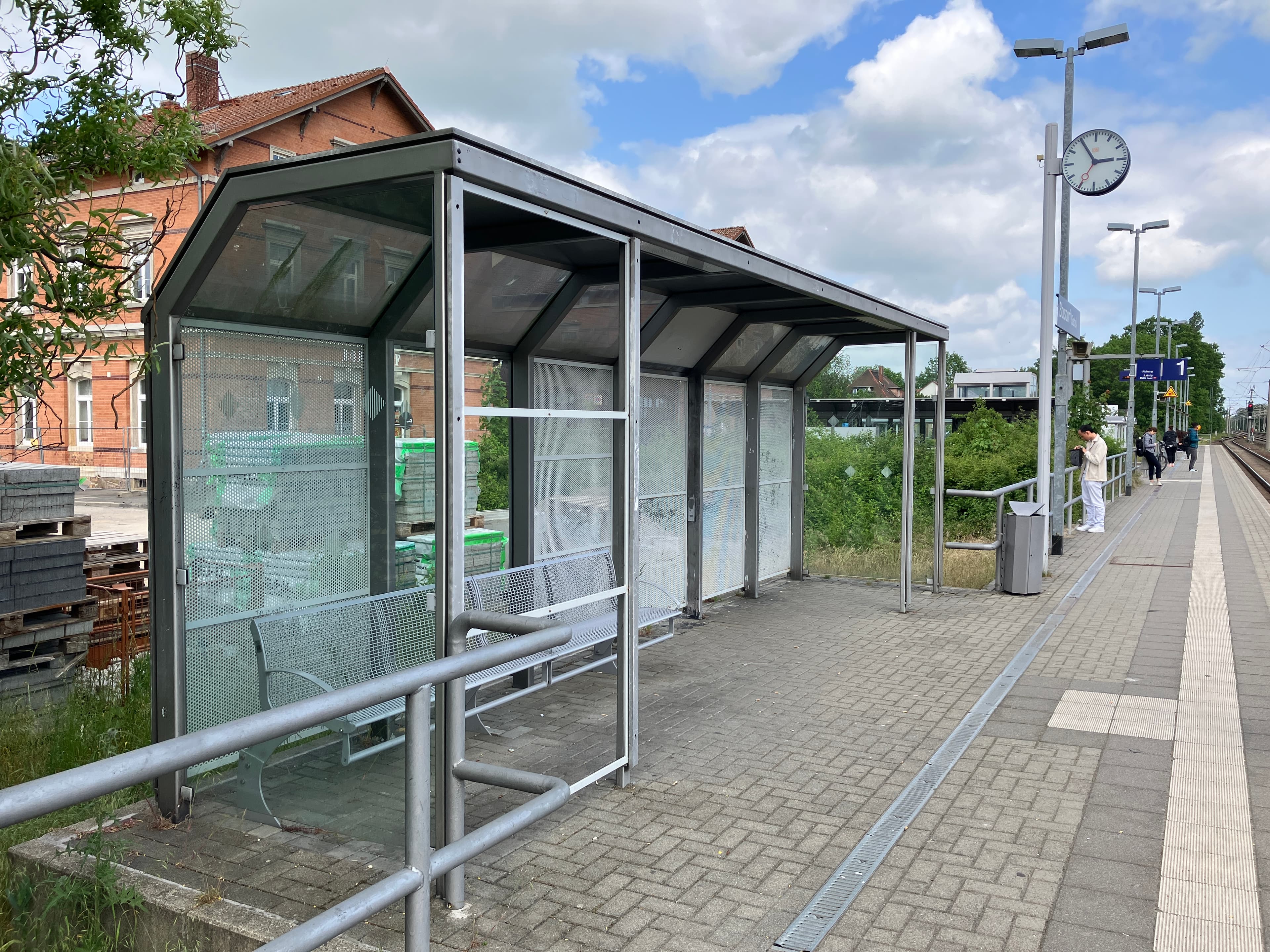 Zu sehen ist eines der alten Wetterschutzhäuser mit graue Blechwände und graue Bänke.