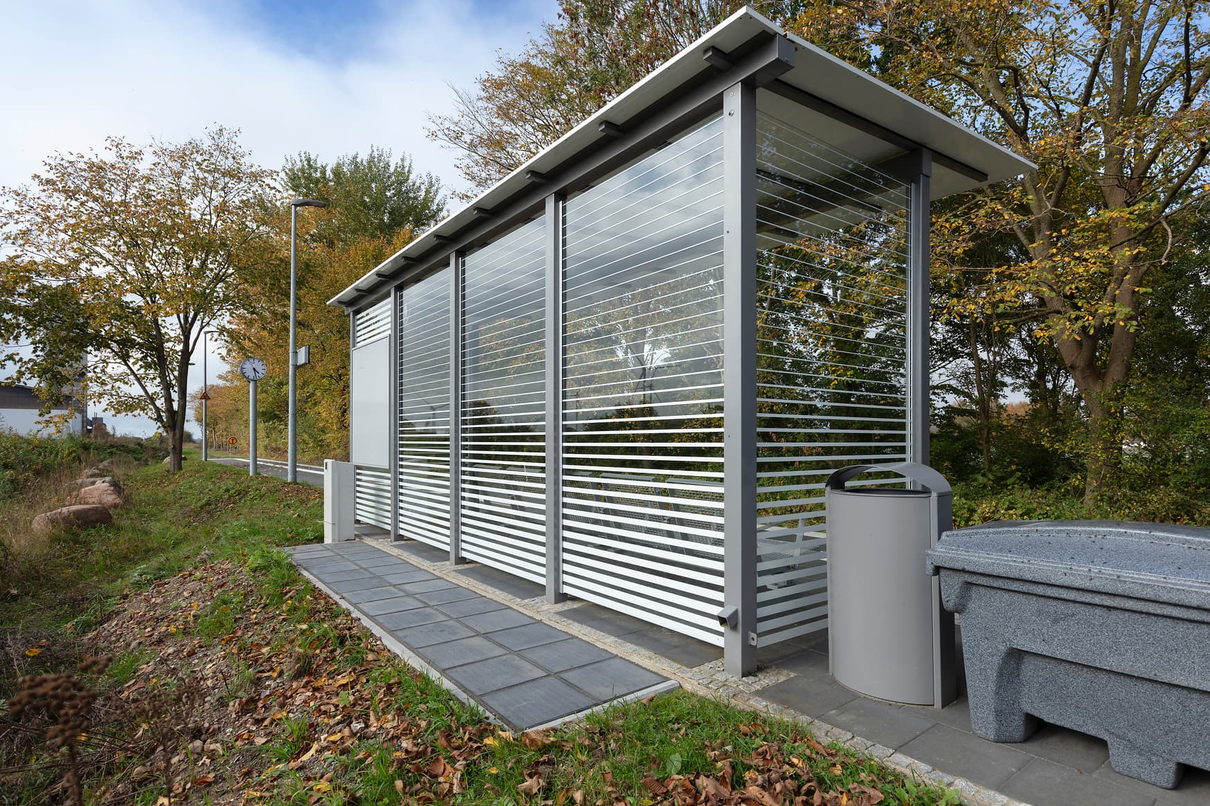 Wetterschutzhäuschen von hinten auf einem Bahnsteig, erkennbar die Solarpanellen auf dem Boden.