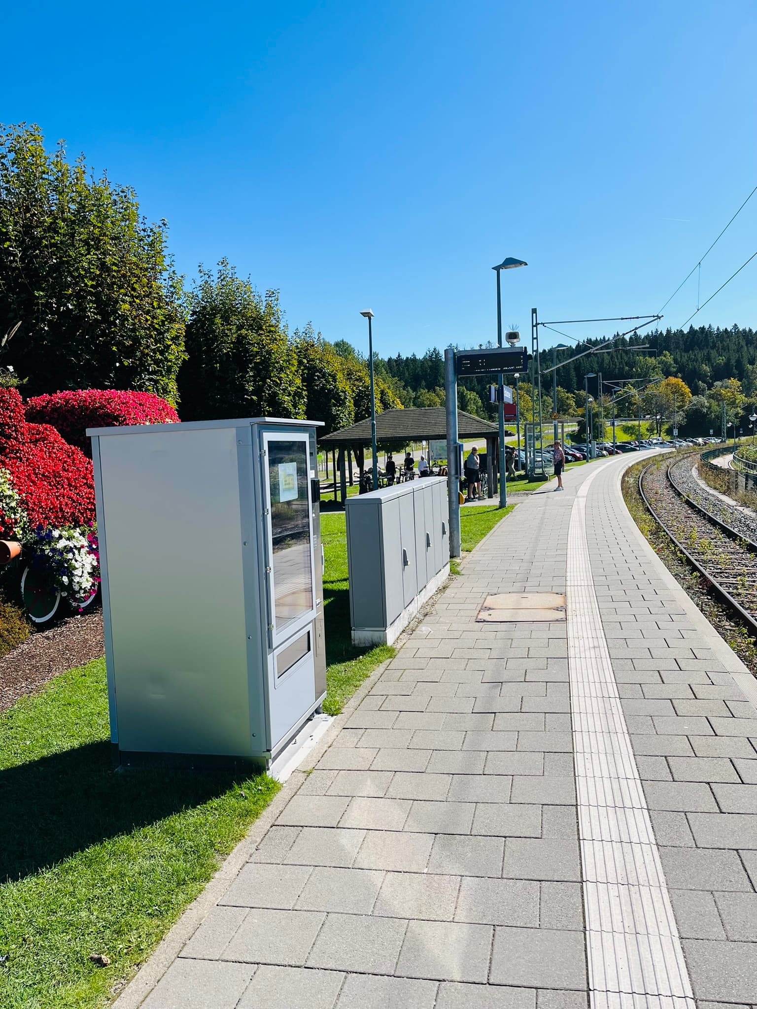Blick über den Bahnsteig des Bahnhofs Schluchsee mit Snackautomat, Wartebereich und Kurve der Gleise.