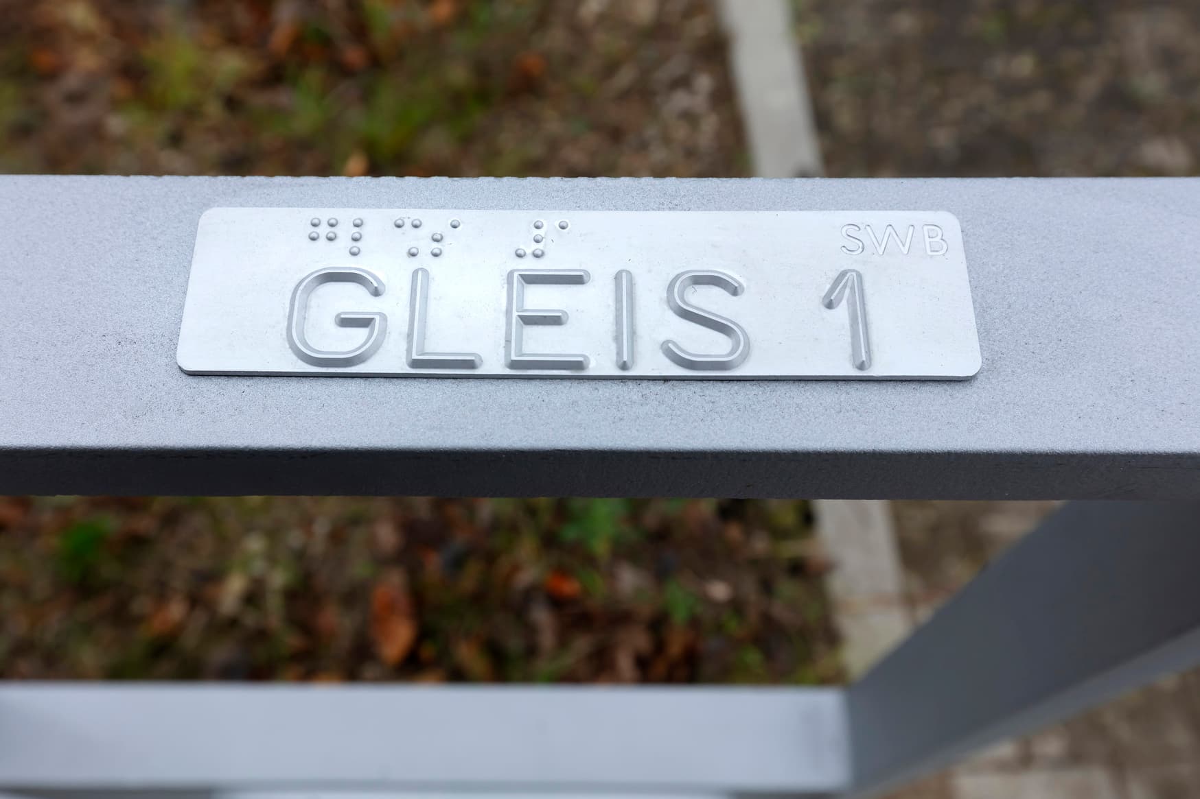 Detailaufnahme der taktilen Wegeleitung am Handlauf des Bahnsteigzugangs.