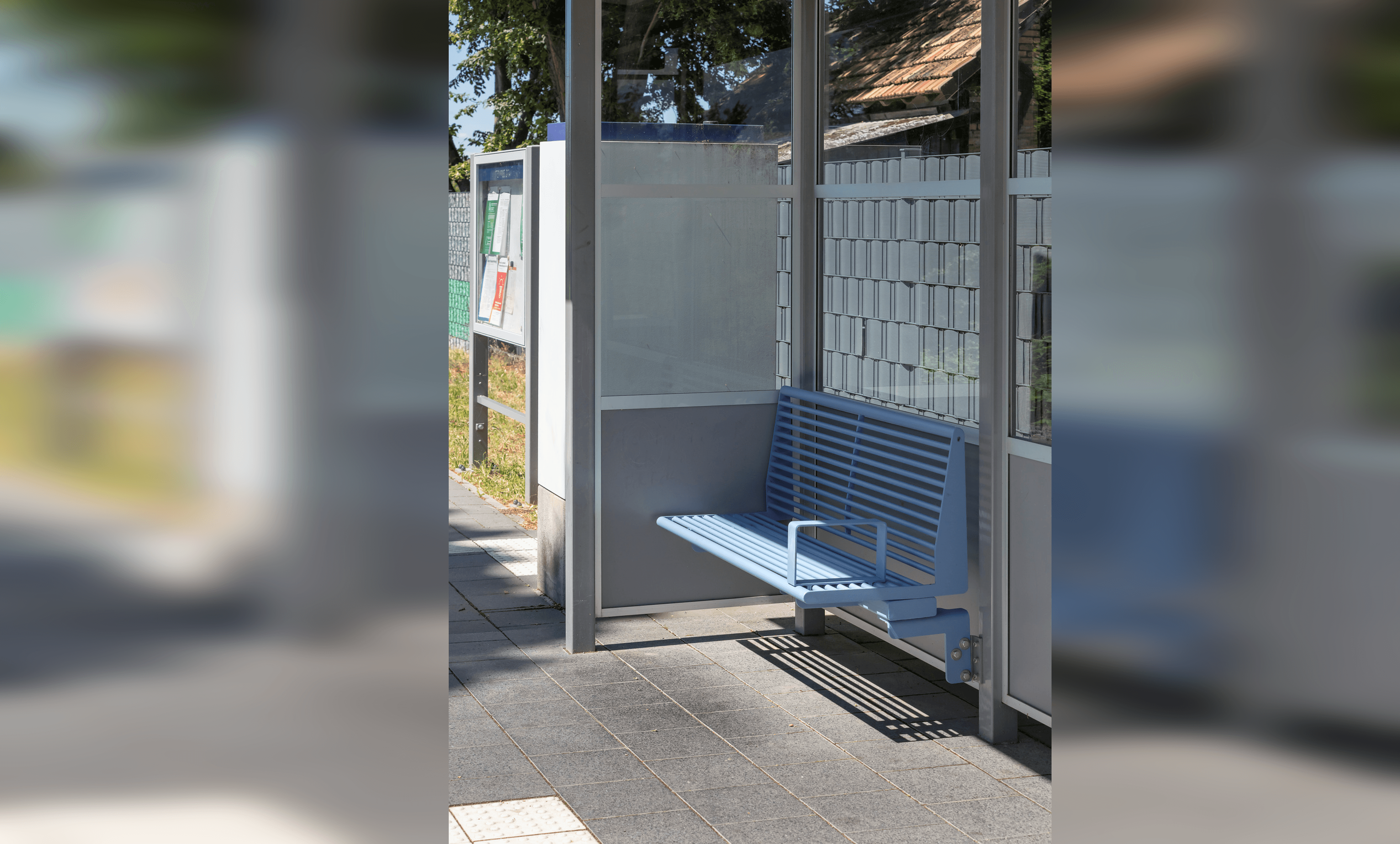 Blaue Sitzbank in einem Wetterschutzhäuschen.