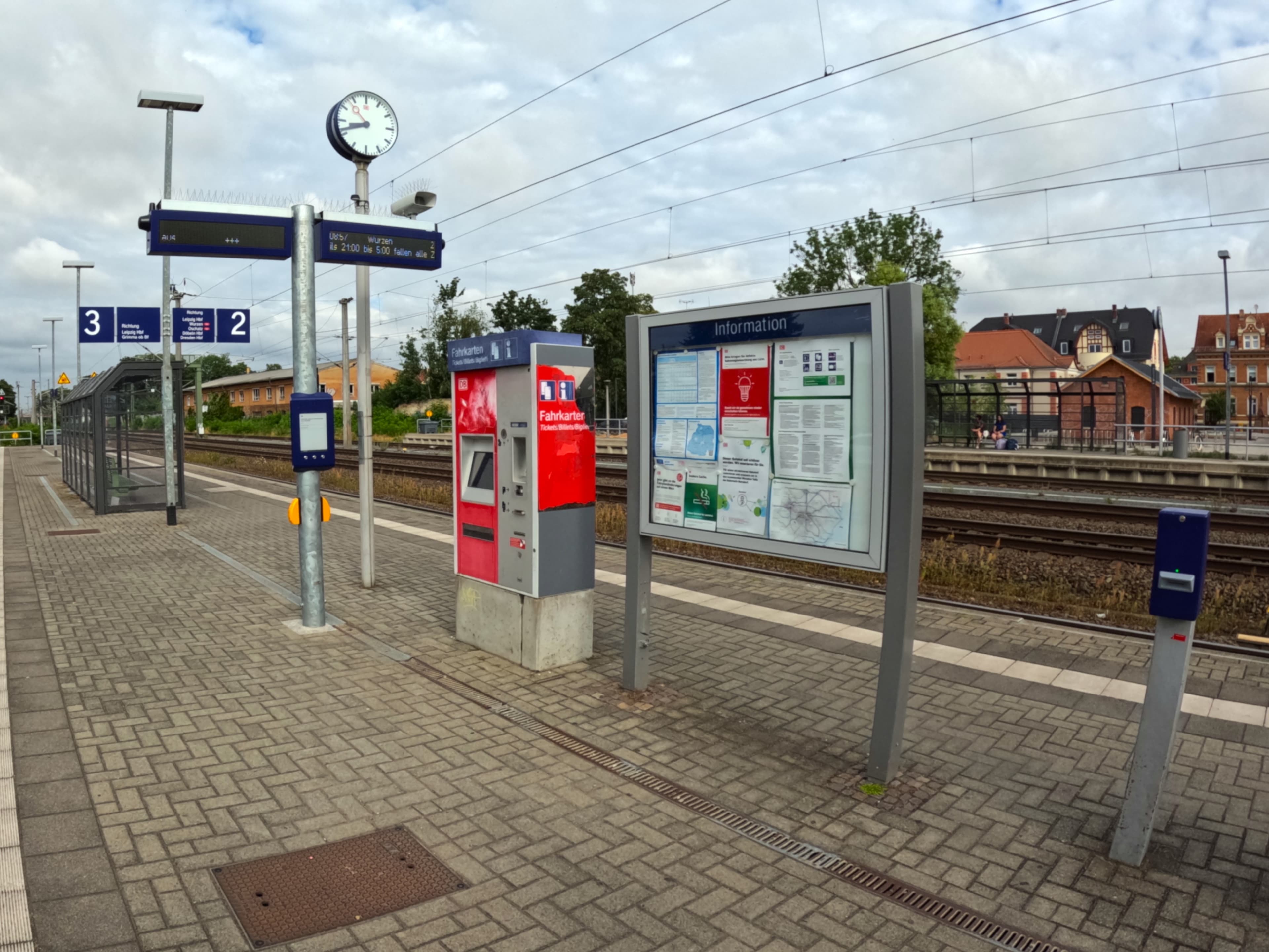 Zu sehen ist der Mittelbahnsteig mit zwei digitalen Zug-Anzeigern und dem neuen digitalen Aushangfahrplan, der die Zugzeiten ansagen kann. 