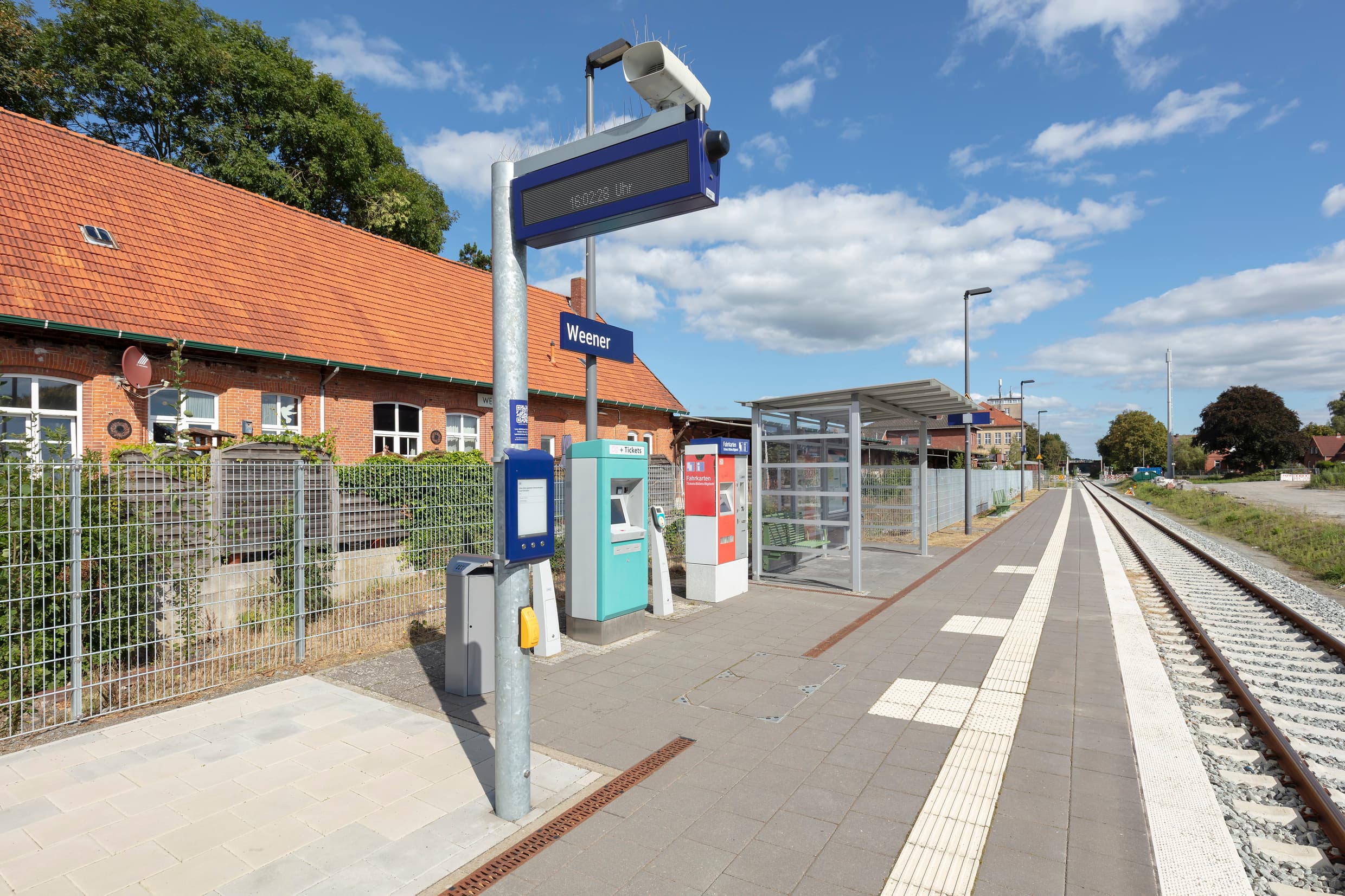 Bahnsteig mit dem neuen zweizeiligen Dynamischen Schriften Anzeige, dem Digitalen Aushang Baukommunikation (DAB), einem neuen Wetterschutzhaus und einer neu gepflasterten Bahnsteigfläche.