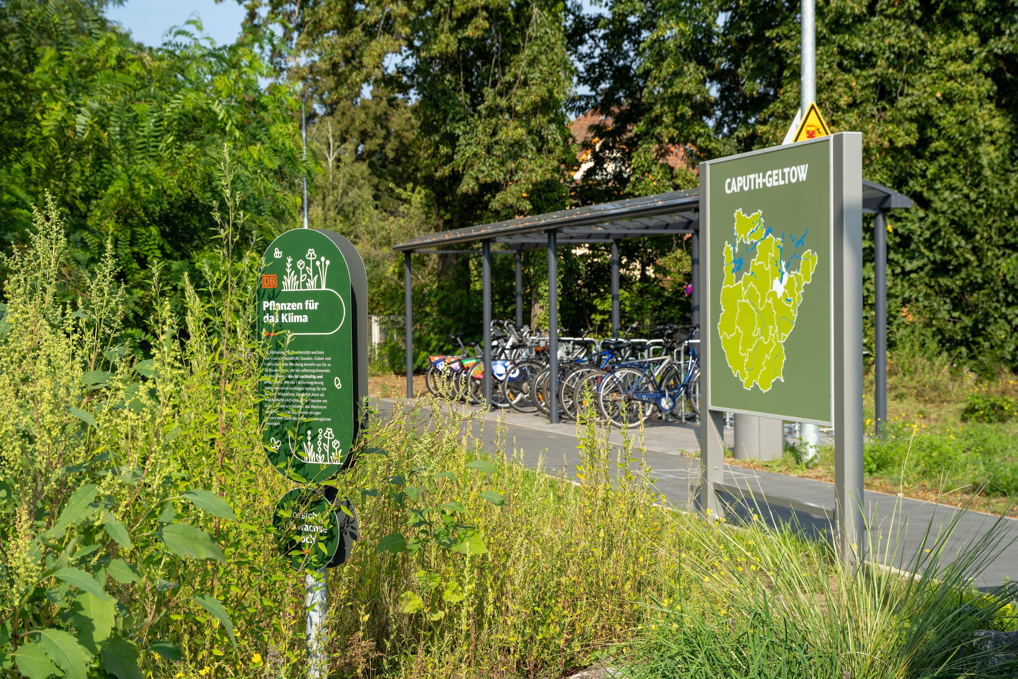 Grüne Schilder mit Infos zur Region und ein Fahrradparkhaus.
