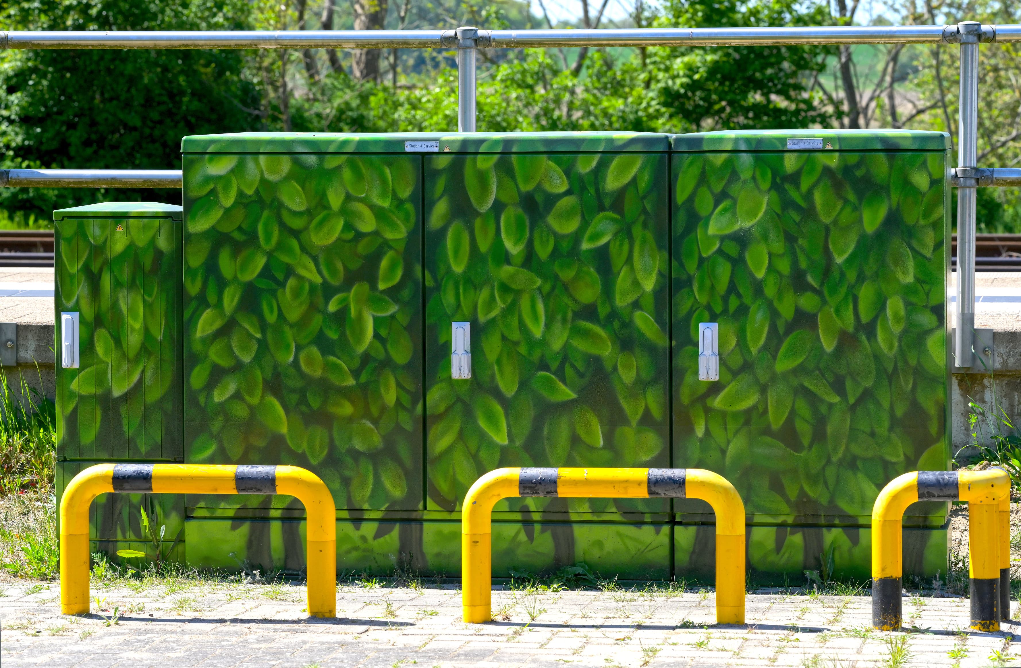 Blick auf gelbe Schutzvorrichtungen vor einem bunt gestalteten Stromkasten.