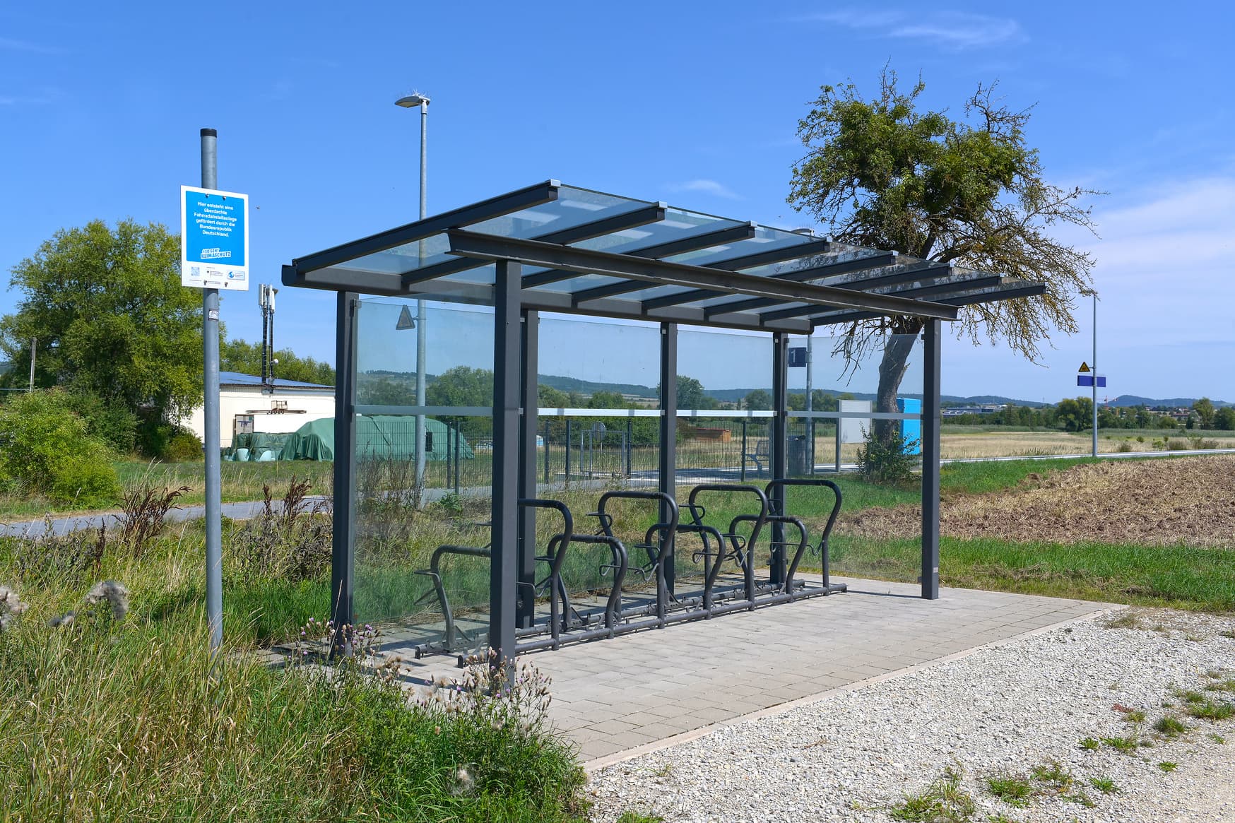 Fahrradabstellanlage mit verglaster Überdachung und dunkel angestrichenen Fahrradbügeln.