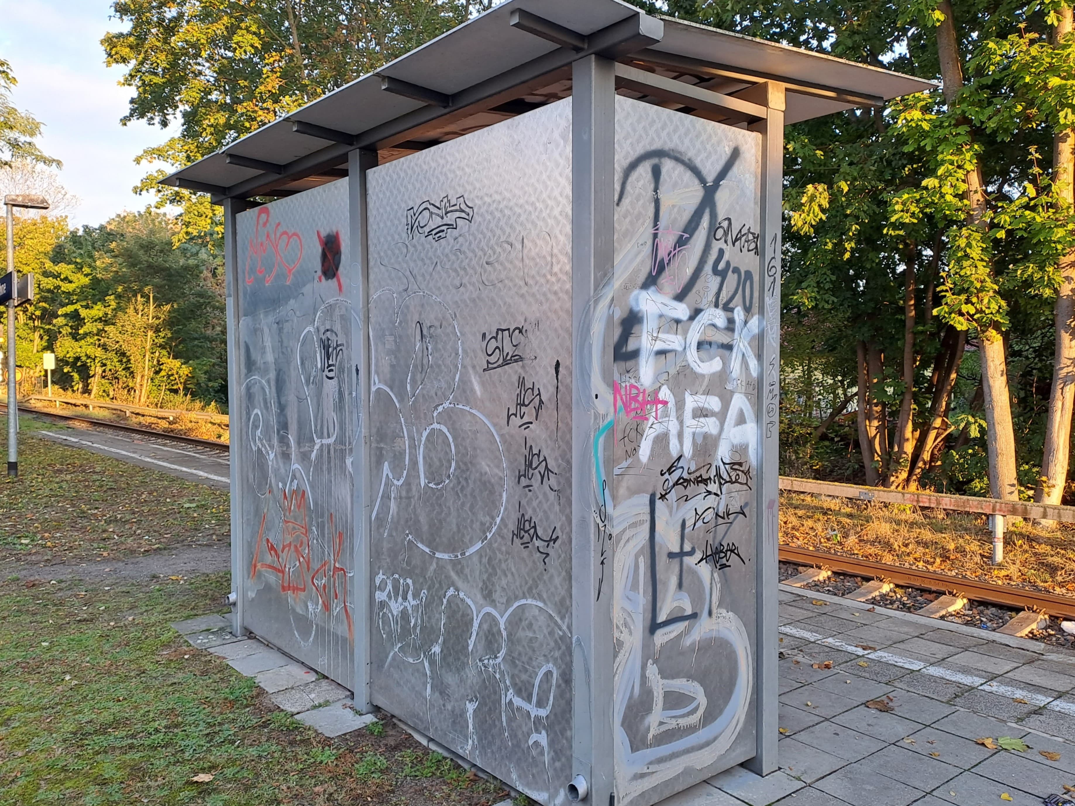 Ein Wetterschutzhäuschen von hinten, mit Graffiti.