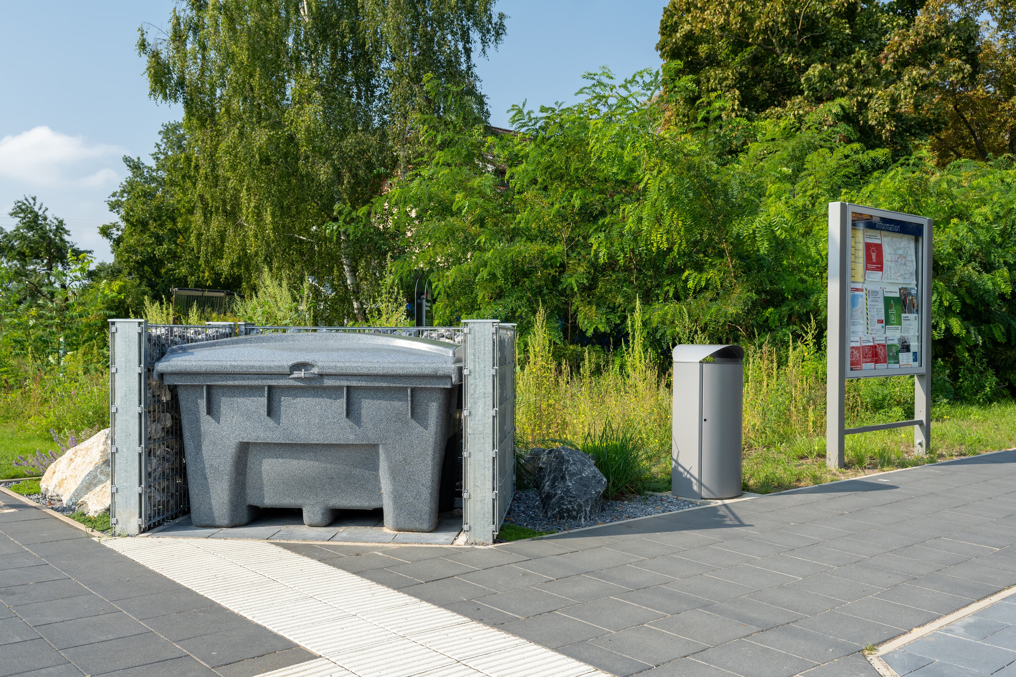 Ein Streugutbehälter, ein Mülleimer, eine Glasvitrine mit Informationen.