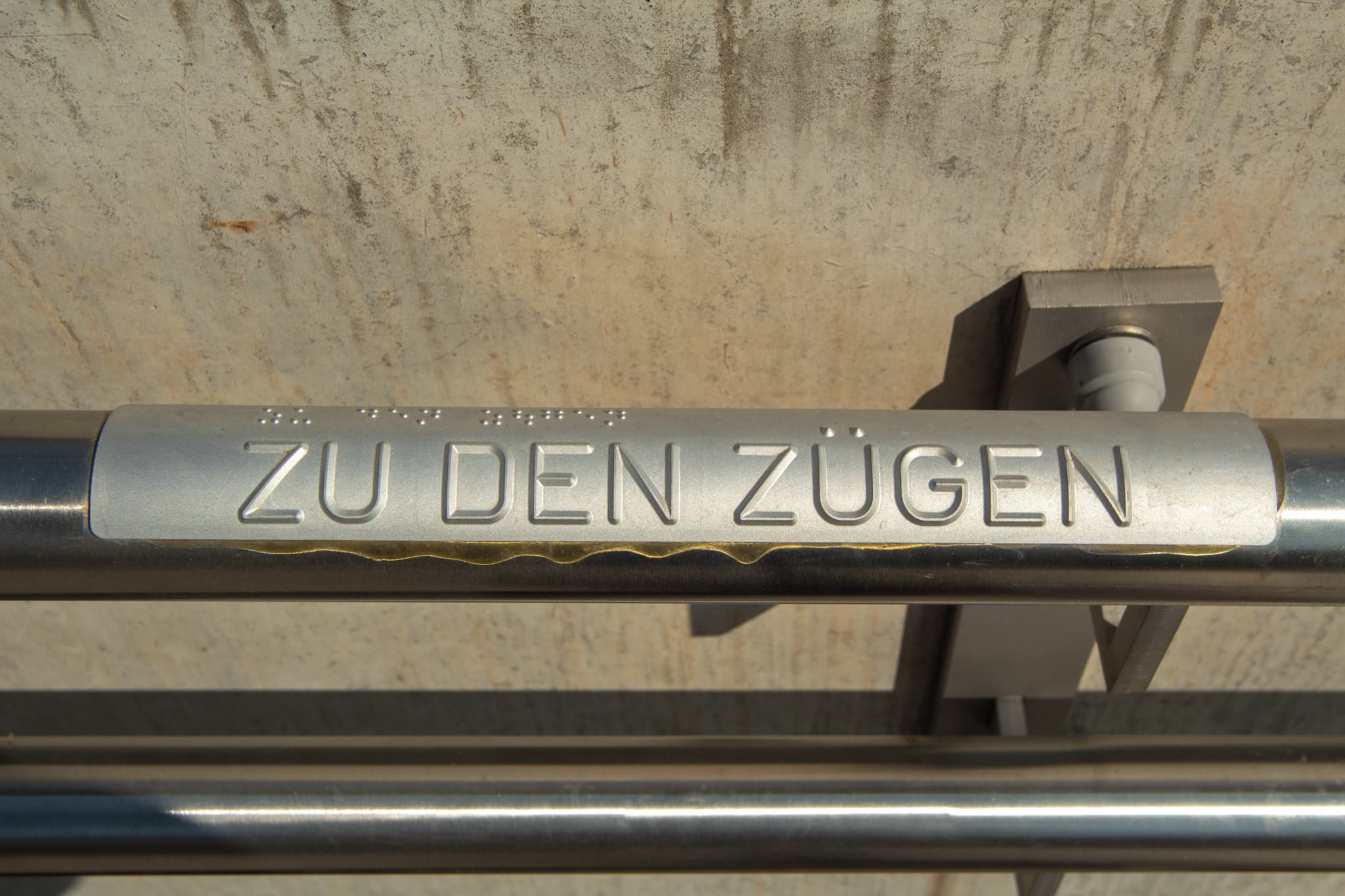Taktiles Handlaufsystem mit der Aufschrift "Zu den Zügen".