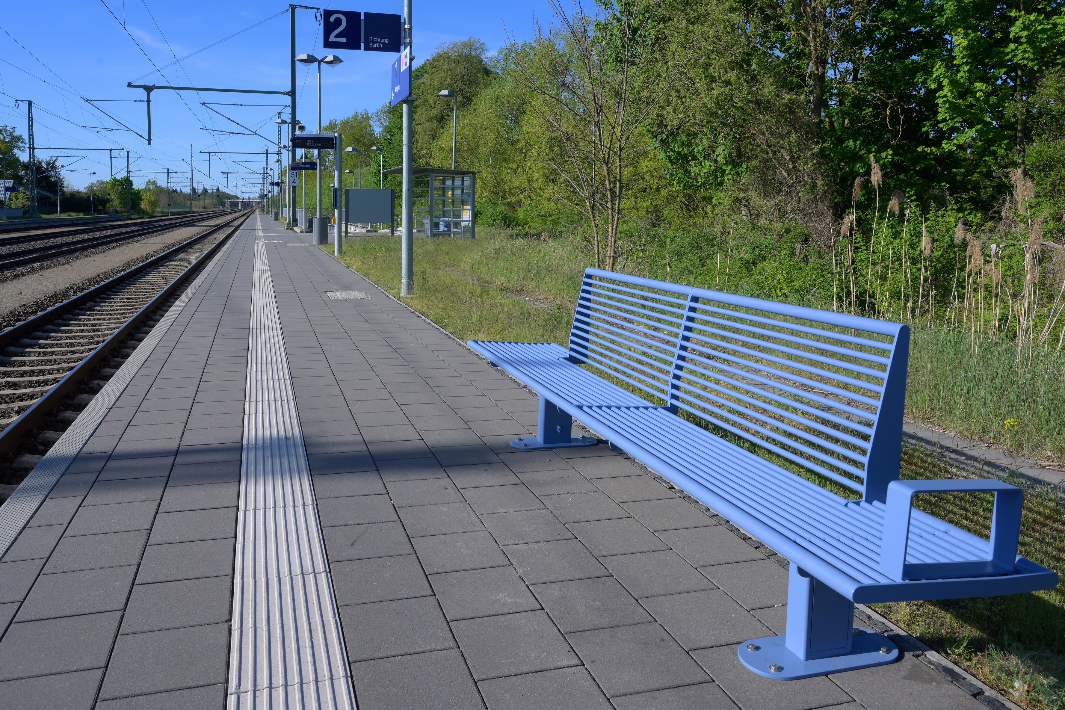 Ein Bahnsteig mit hellblauer Sitzbank.
