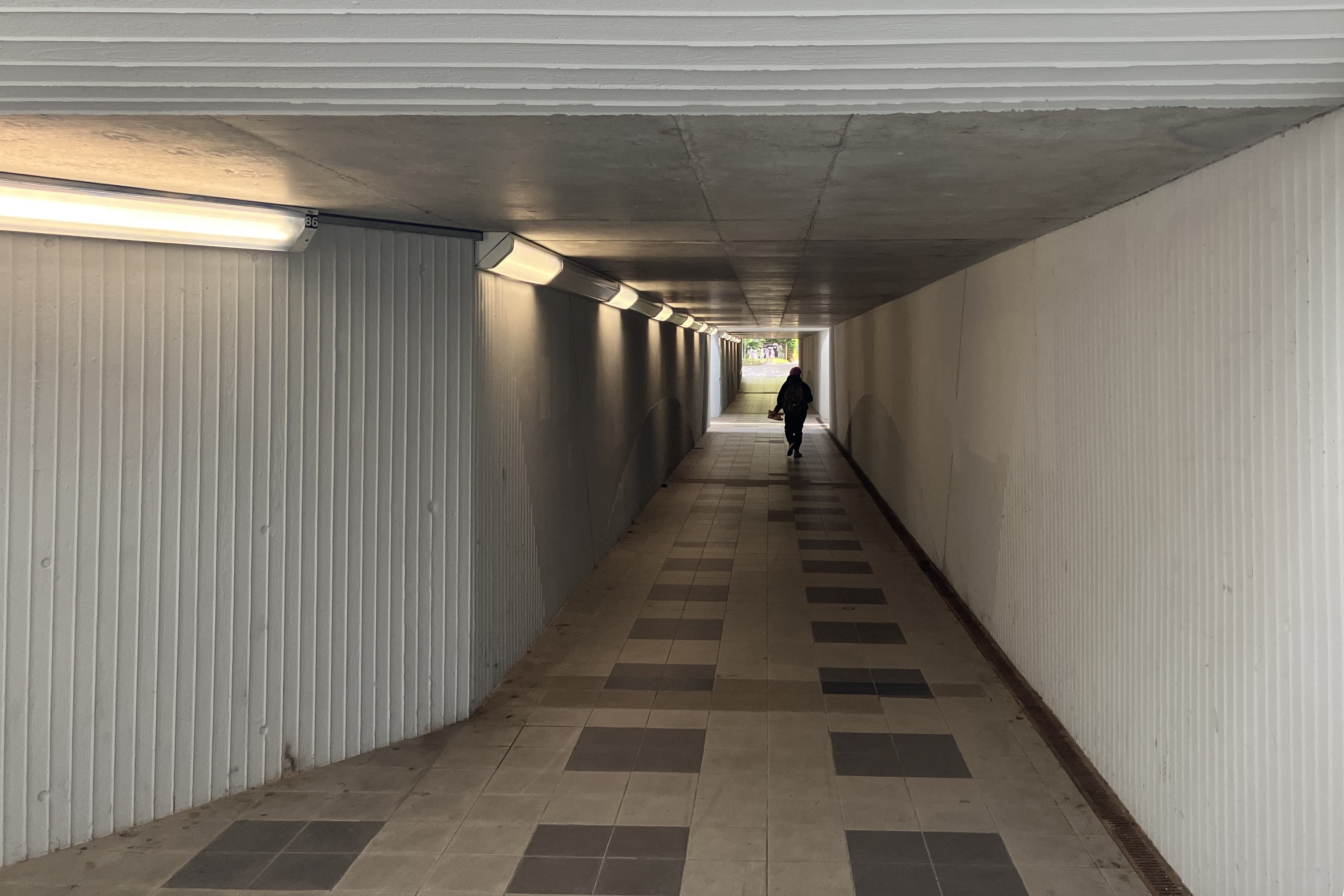 Zu sehen ist der Fußgängertunnel in Borsdorf vor der Erneuerung. Die Wände sind hellgrau, der Tunnel wirkt dunkel. 