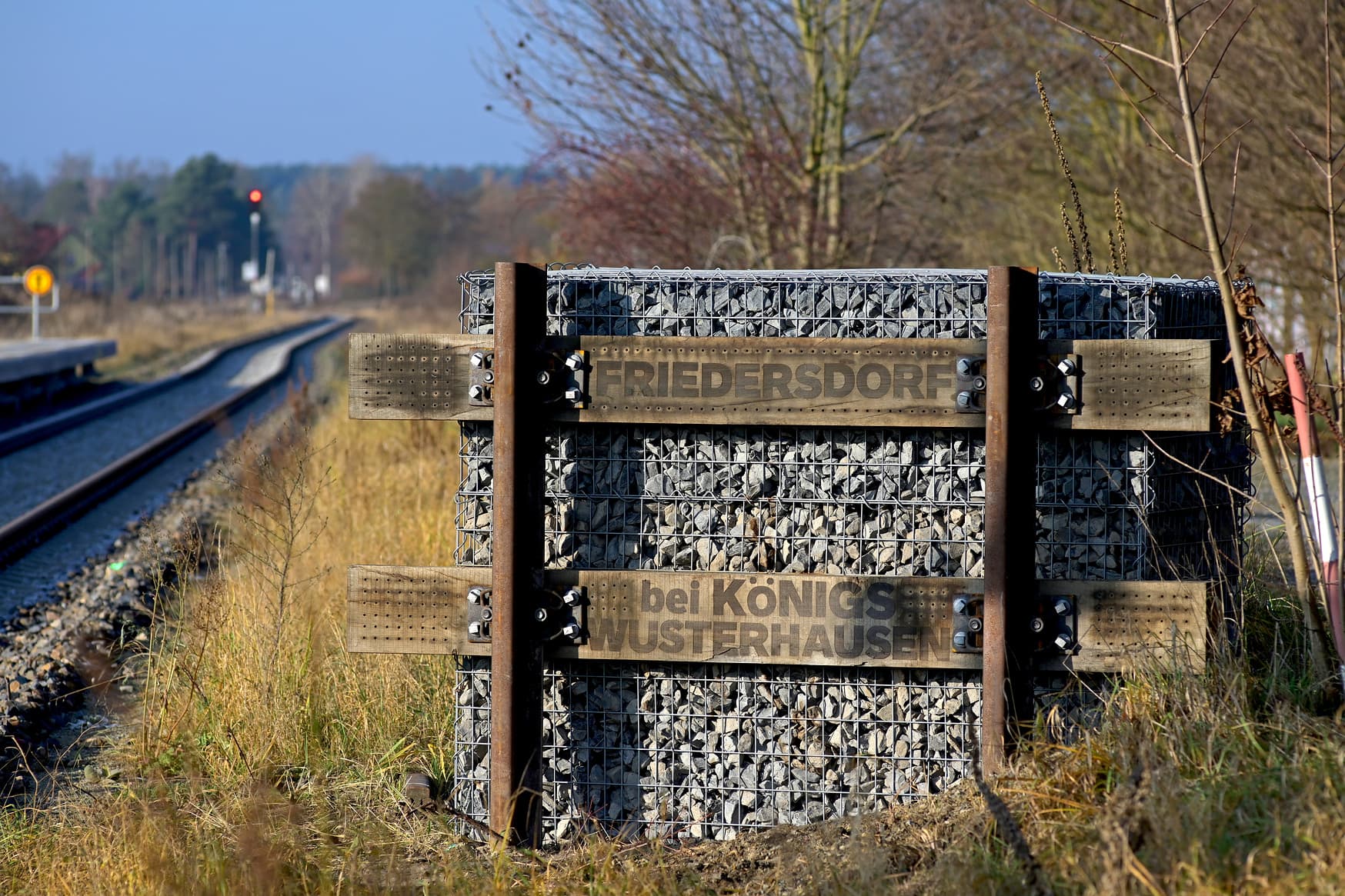 Bahnhofsschild aus Holz und Stein.