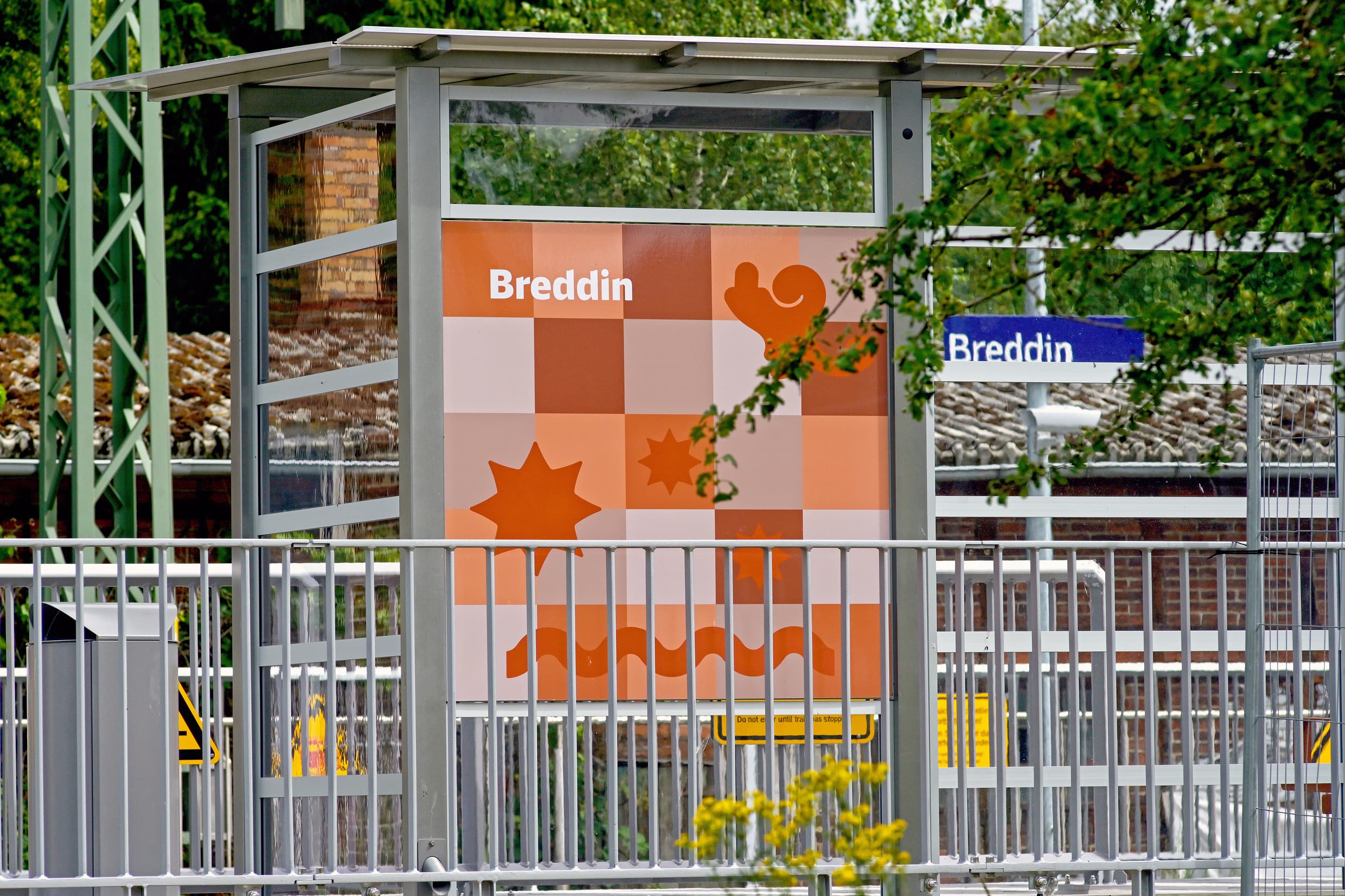 Bunt gestaltete Vitrinen-Rückwand am Bahnhof Breddin.