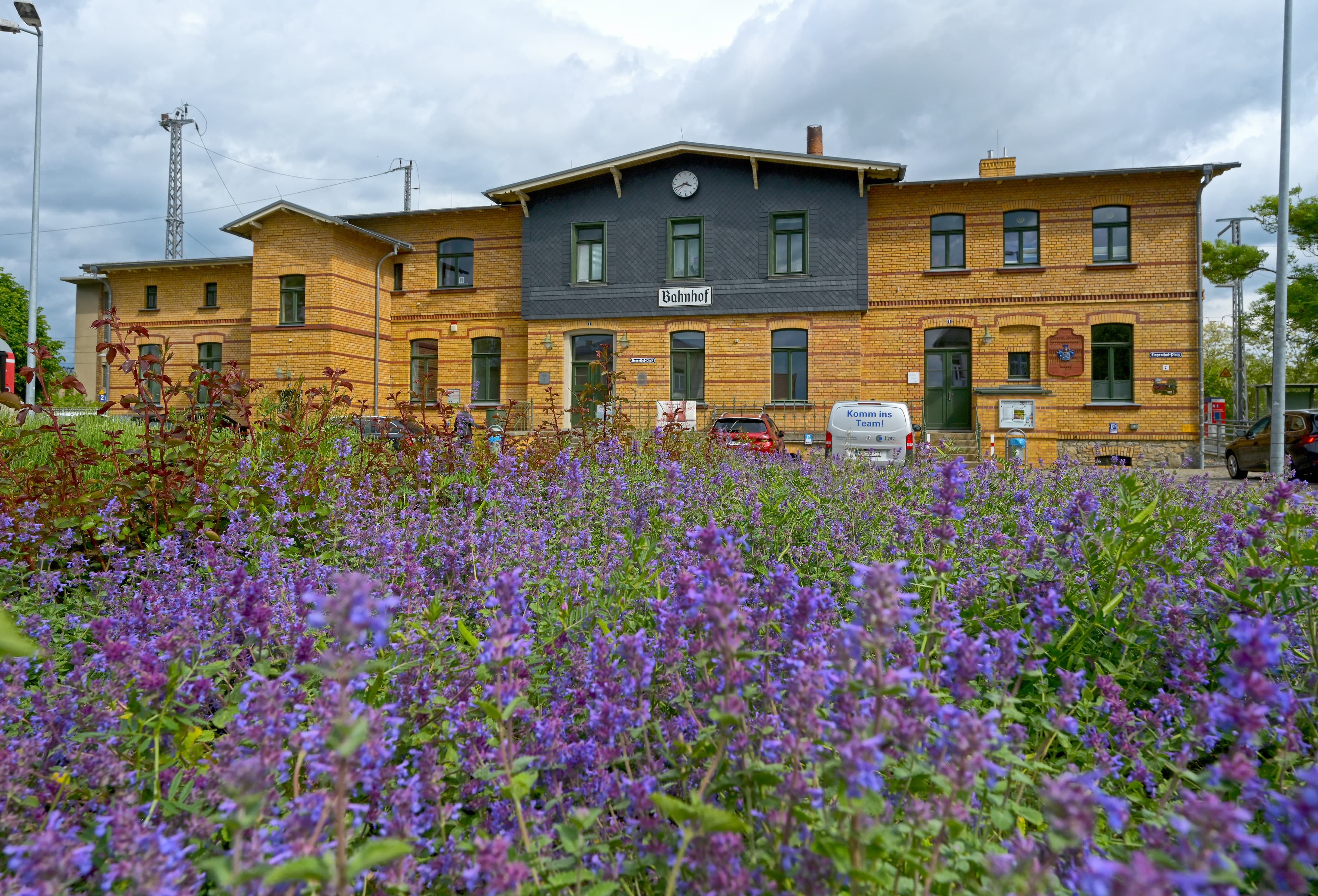 Das Empfangsgebäude des Zukunftsbahnhofs Ortrand vor einer Blumenwiese.