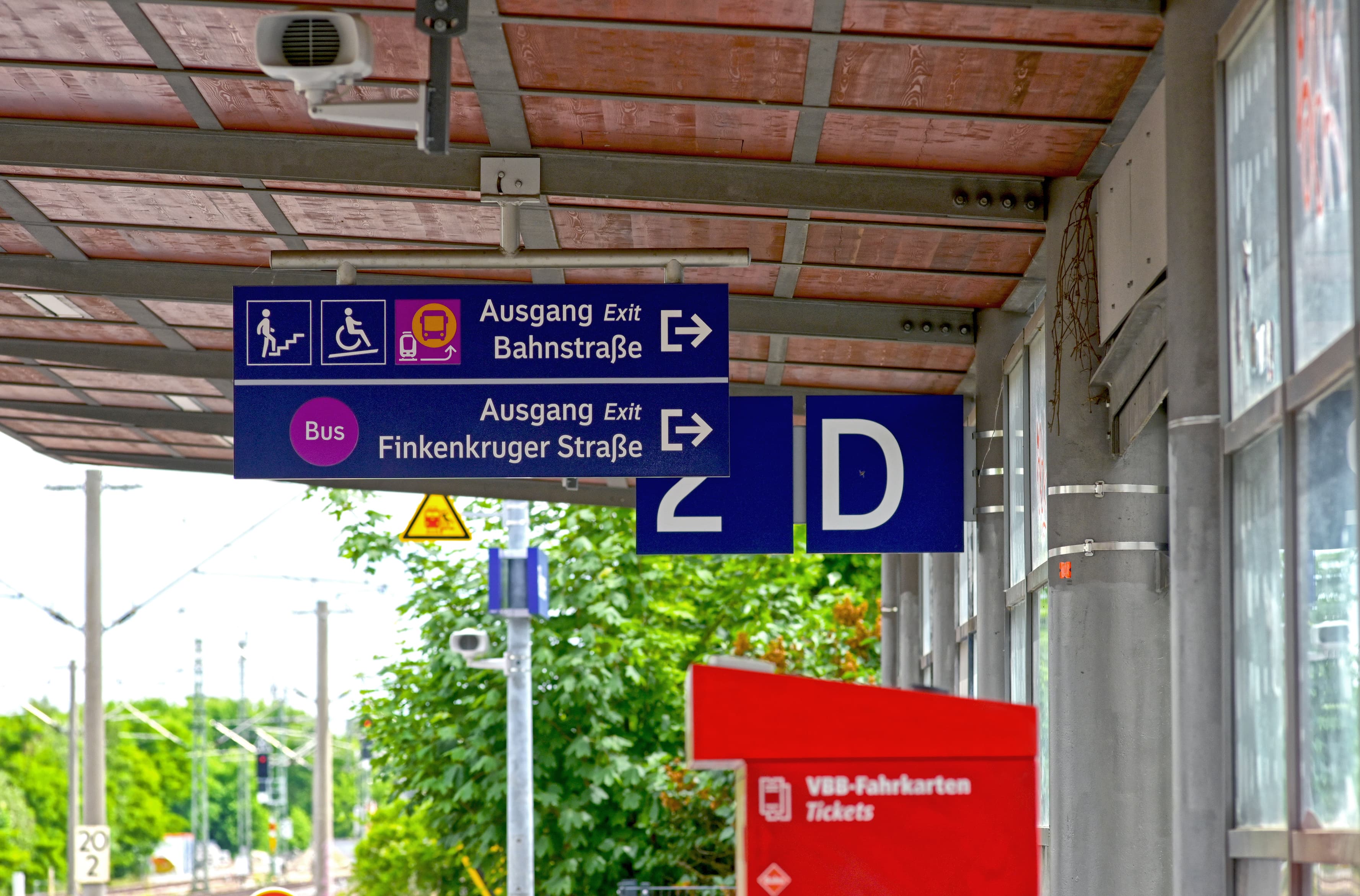 Blaue Wegweiser an einem Bahnsteig.