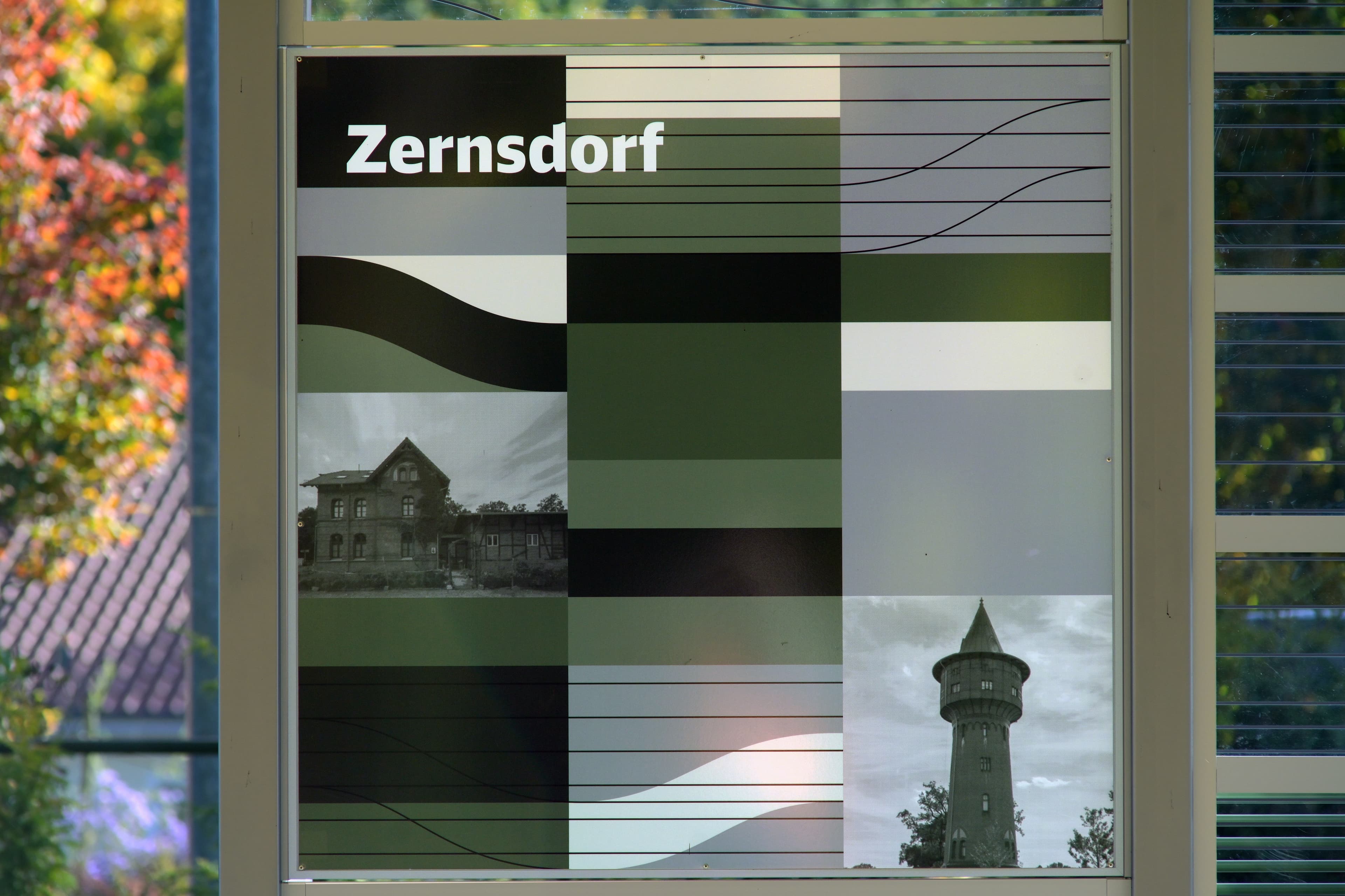 Blick auf eine grün-grau gestaltete Rückwand eines Wetterschutzhauses. 