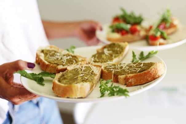 Kellner serviert ansprechend angerichtete Bruschetta auf weißen Porzellantellern.