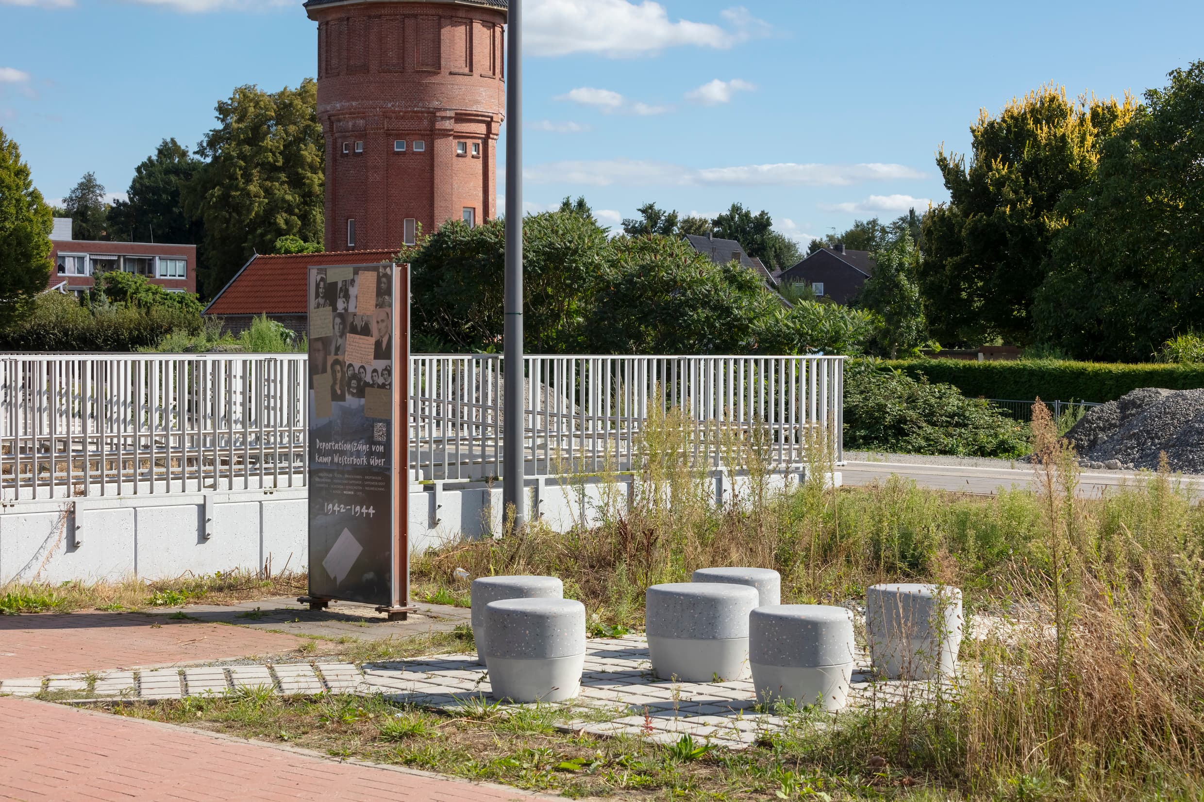 Bahnhofsvorplatz mit neuen Betonhockern und dem neuen Geländer am Bahnsteigzugang am Bahnhof Weener.
