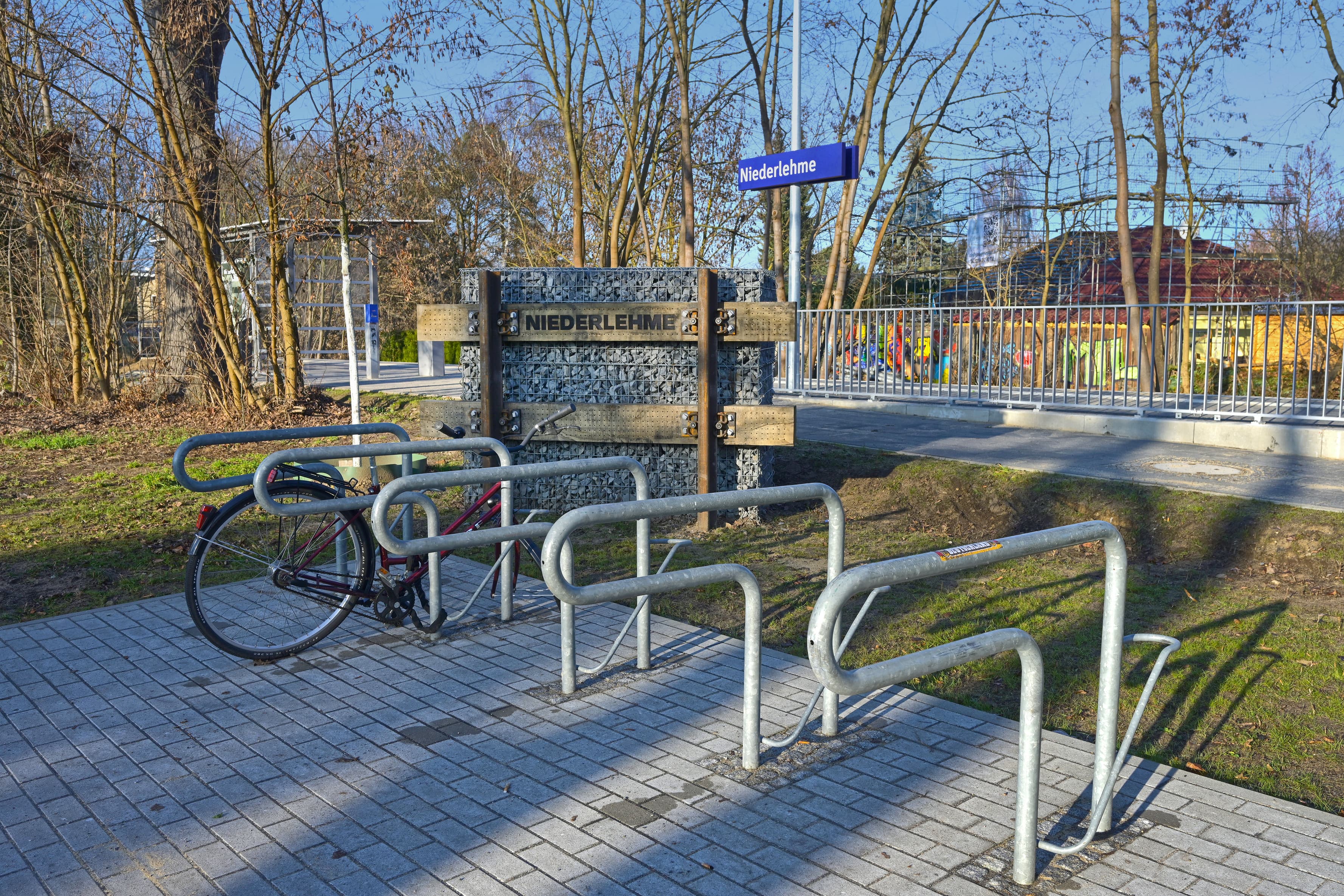 Fahrradbügel und Bahnhofsschild auf dem Vorplatz.