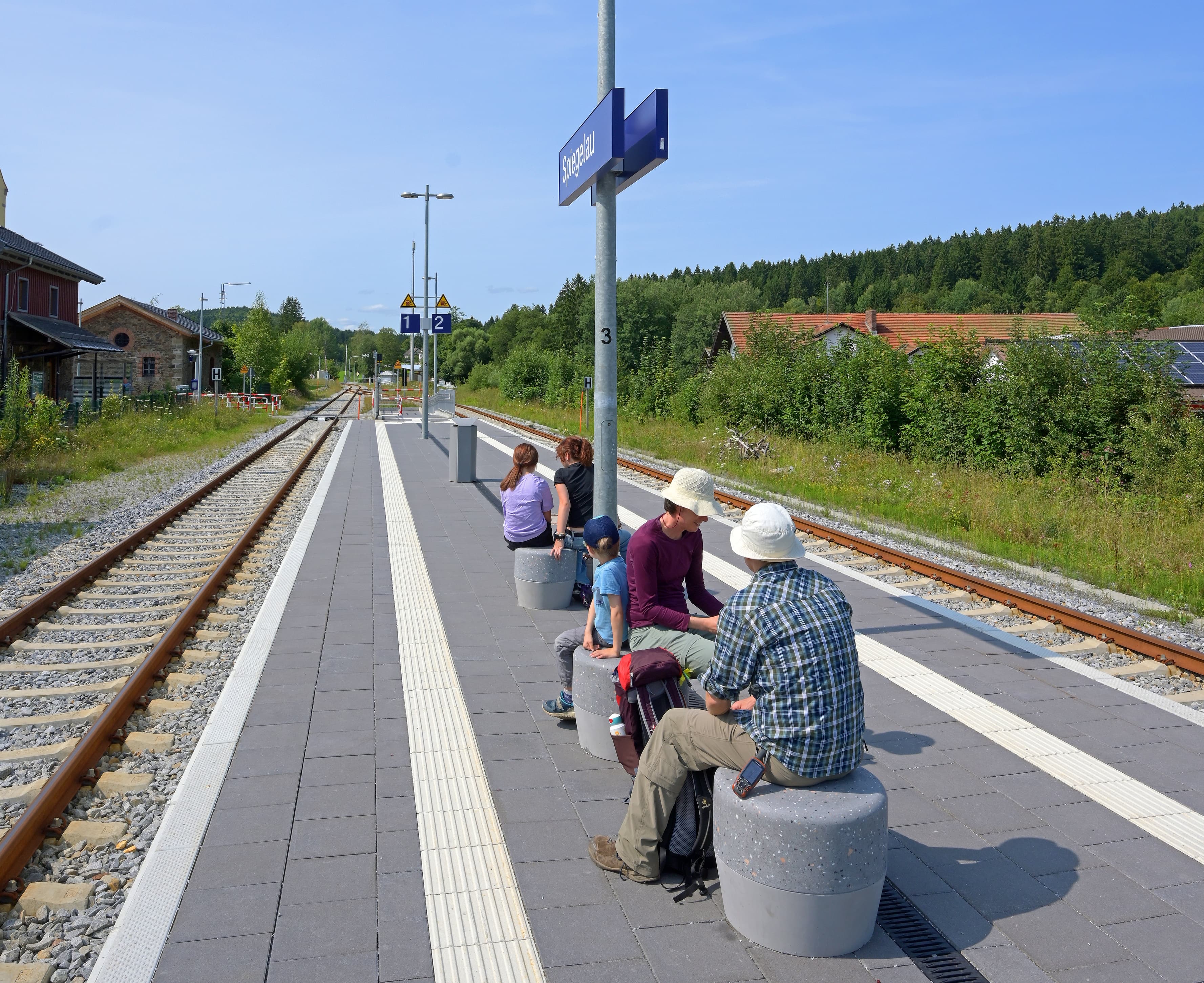 Die modernen Sitzgelegenheiten am Bahnsteig zwischen Gleis 1 und 2.  Links und rechts davon die Gleise. Davor die Bahnsteigkante mit taktilem Leitsystem.