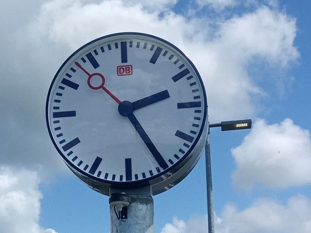 Bahnhofsuhr vor bewölktem Himmel.