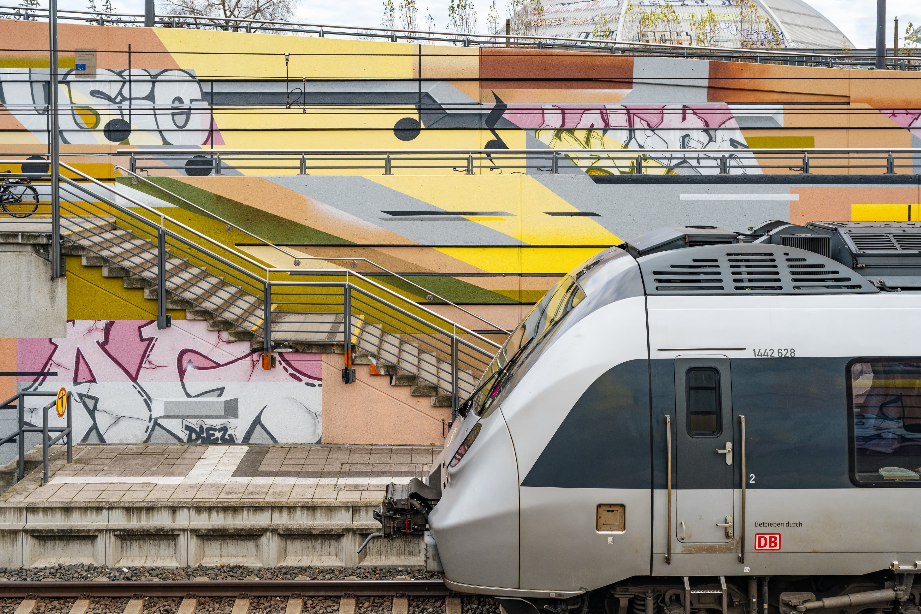 Man sieht die bunt gestalteten Wände mit den Musiknoten und der Sbahn, die am Bahnsteig hält.