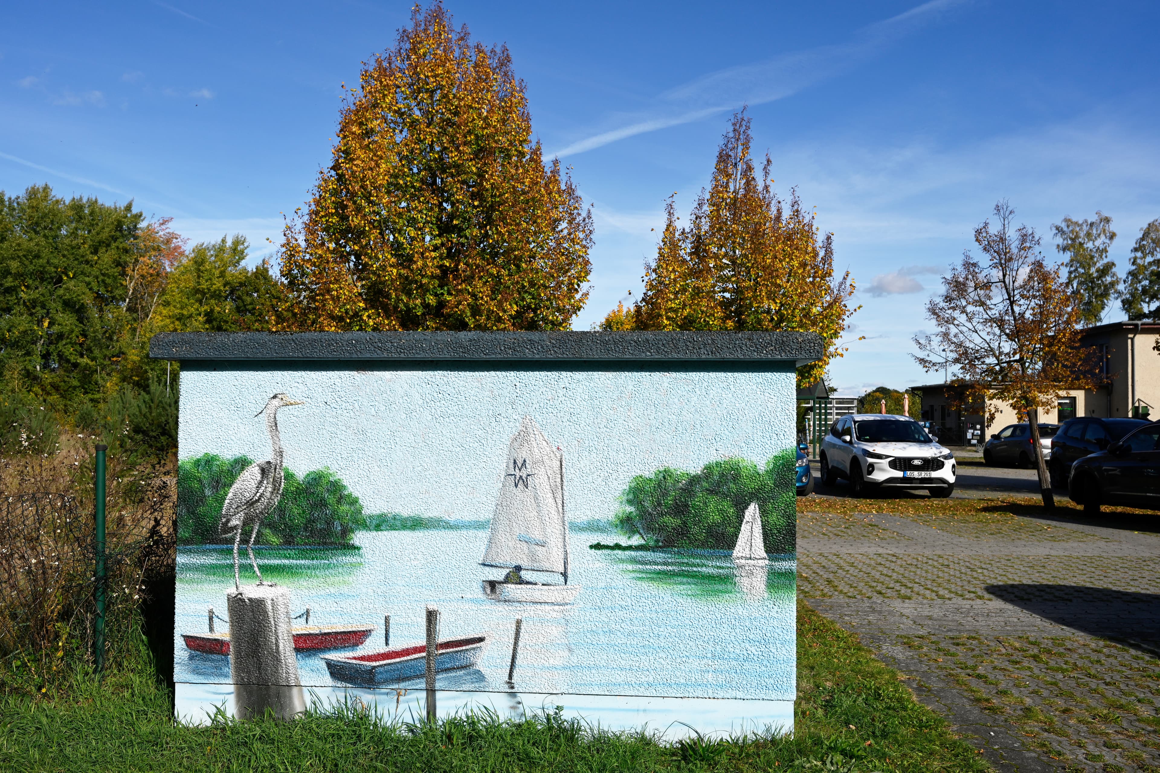 Blick auf bemalte Stromkasten mit Vogel, Wasser und Schiff.