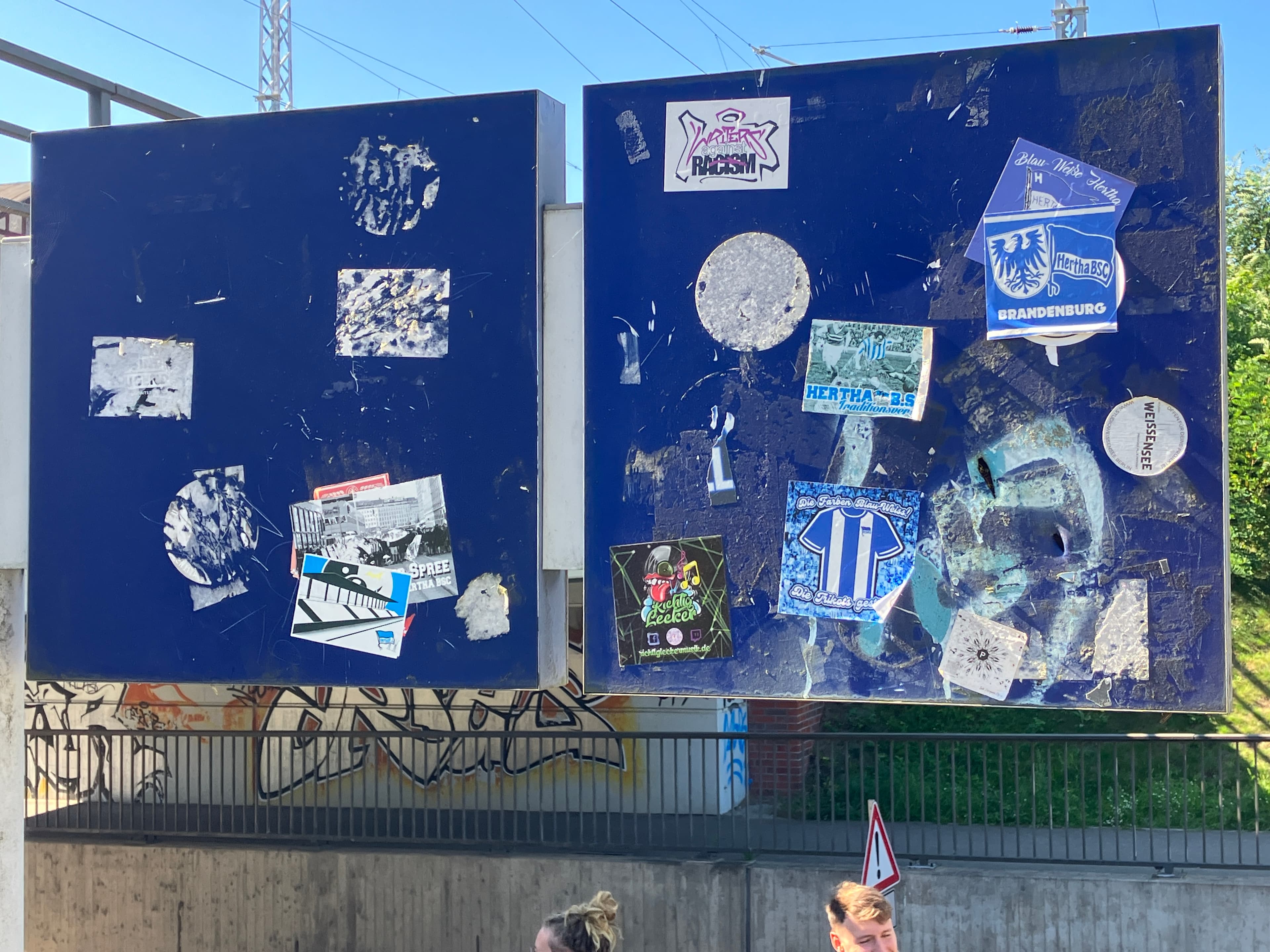 Zwei blaue quadratische Schilder voller Aufkleber. 