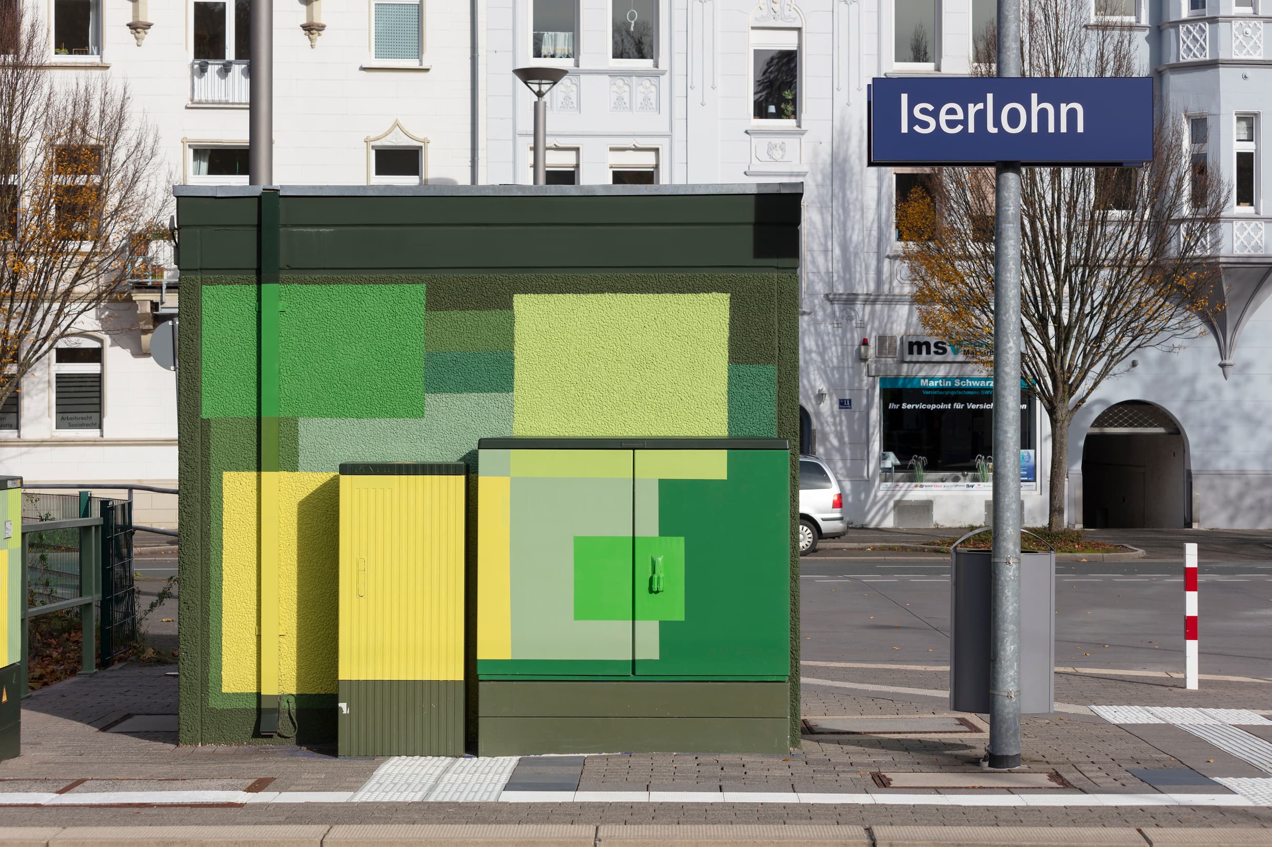 Wandgestaltung des technischen Gebäudes und der Stromkästen mit grünen und gelben Quadraten.