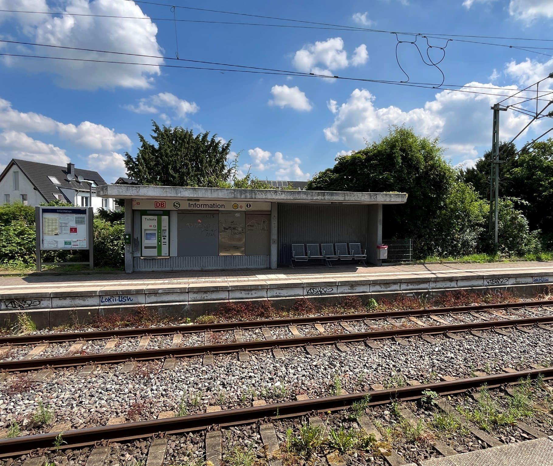 Blick auf zwei Bahngleise. Dahinter ein Bahnsteig mit einem Wetterschutzhäuschen.