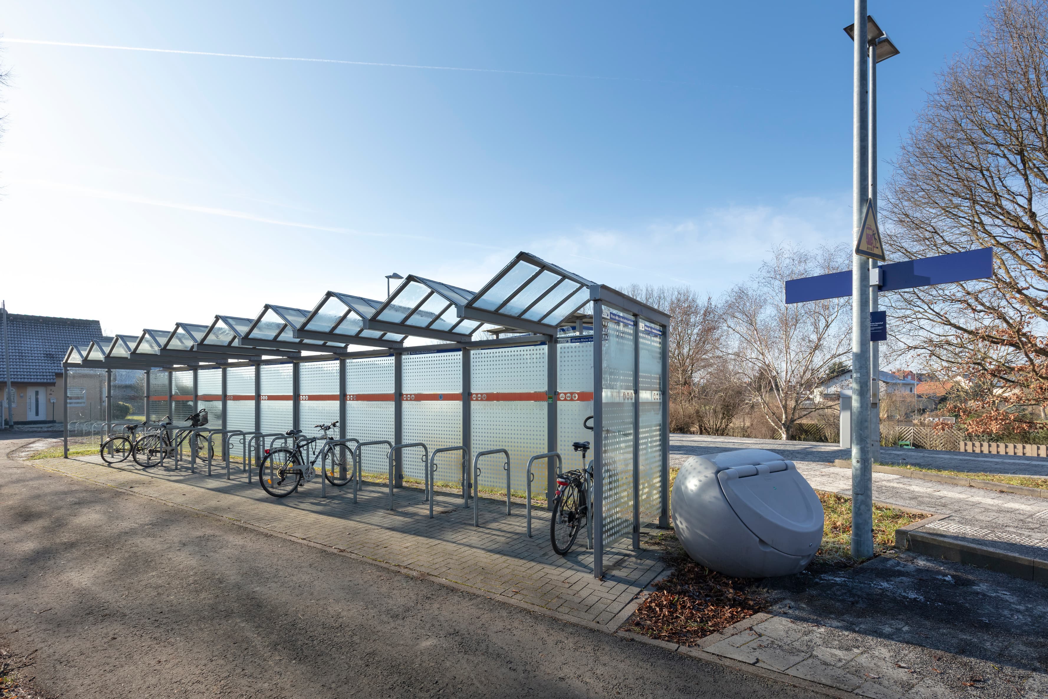 Eine Fahrradabstellanlage mit einem Dach und transparenten Seitenwänden.