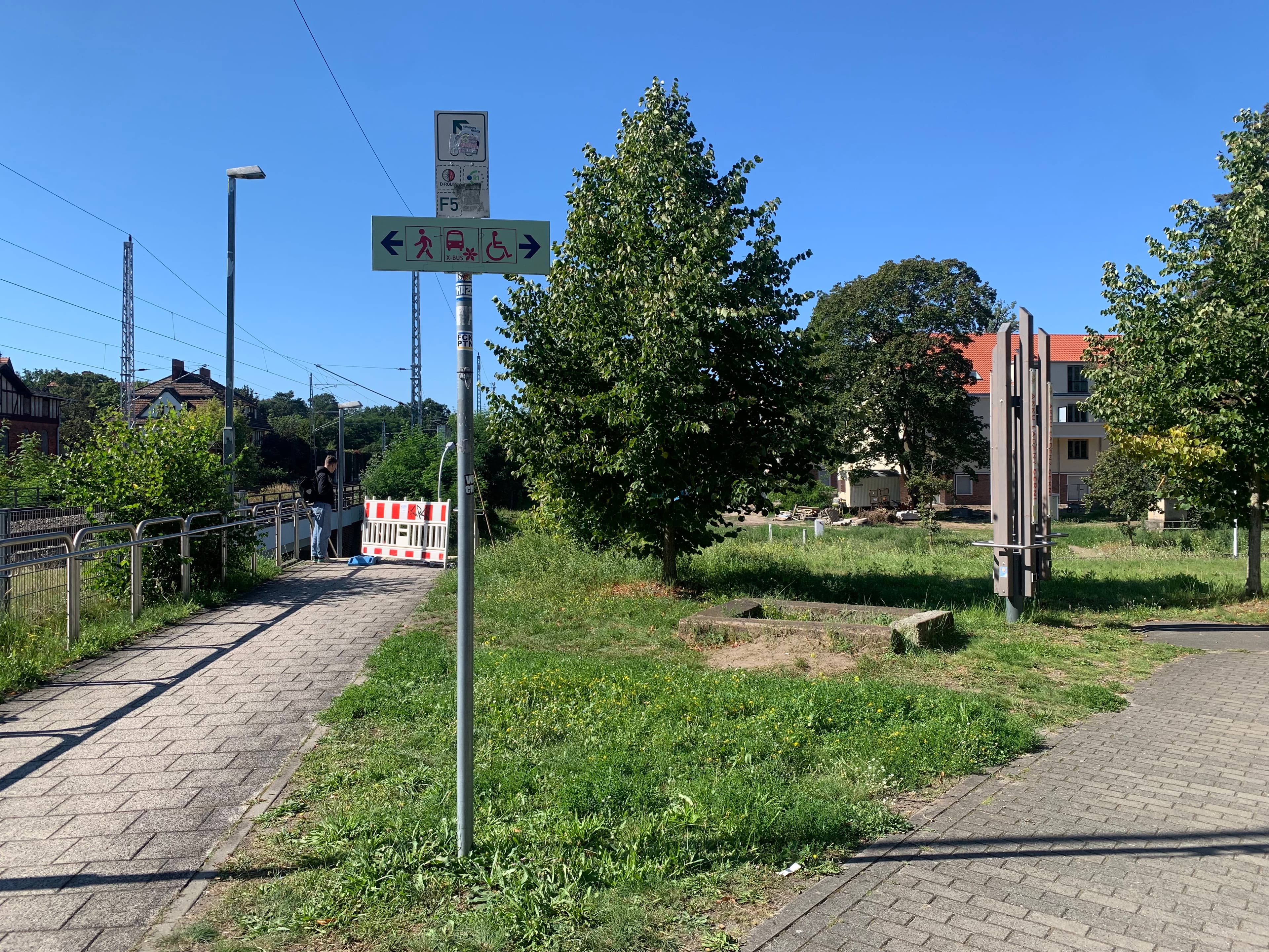 Ein ungenutztes Rasenstück mit einem Wegeschild zwischen zwei Wegen.