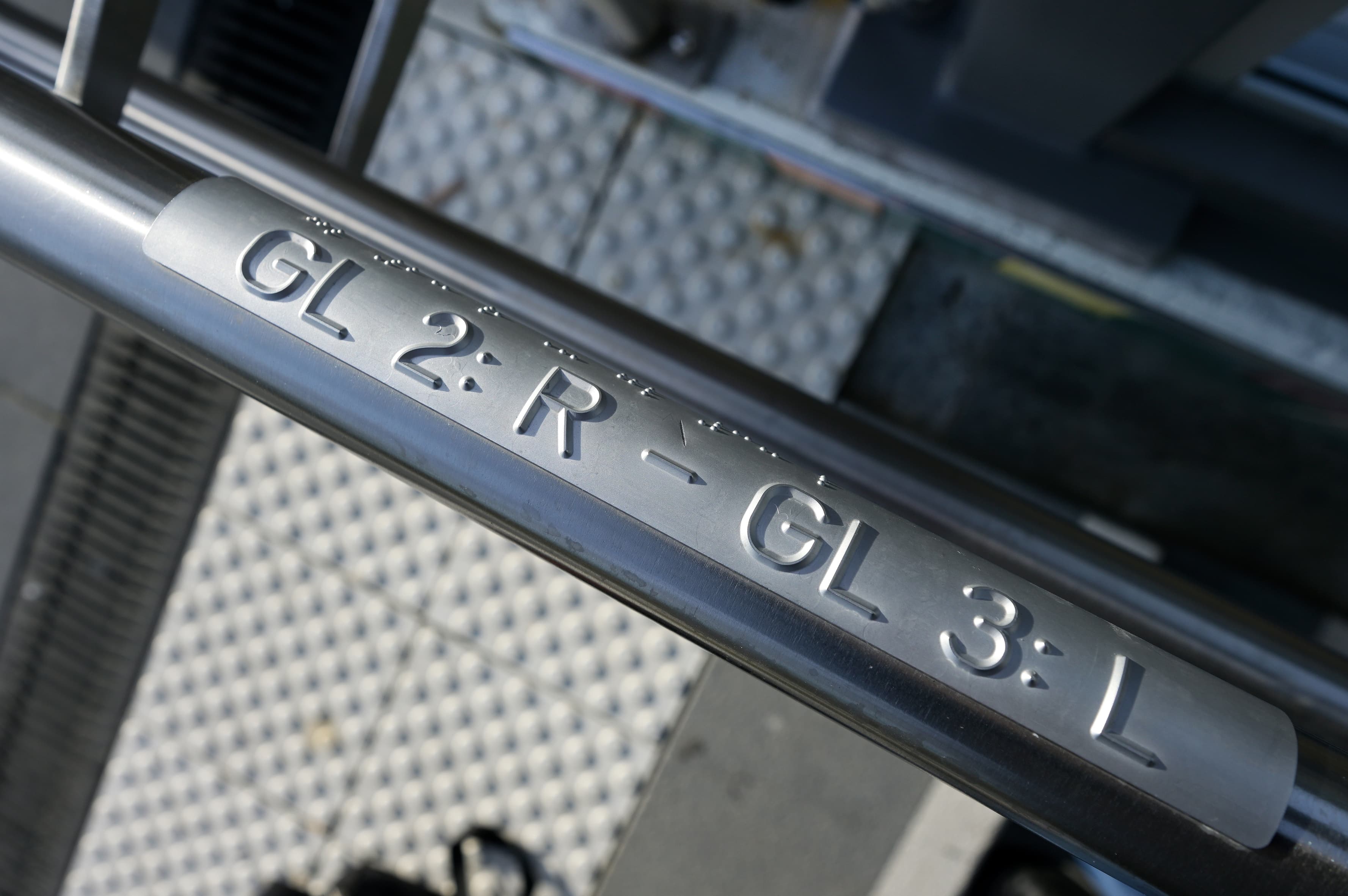 Braille Schrift Schilder an einem Handlauf mit den Hinweisen zu den Gleisen 2 und 3.
