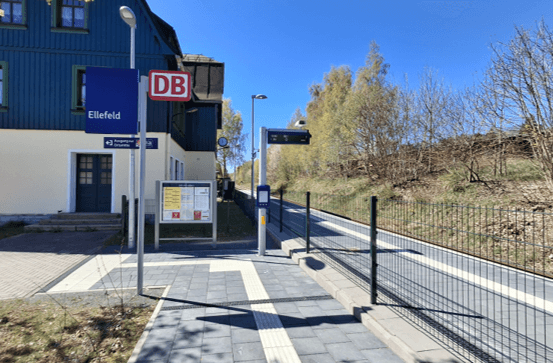 Bahnsteig mit taktilem Blindenleitsystem am Boden. Rechts das Gleis. Links ein Gebäude.