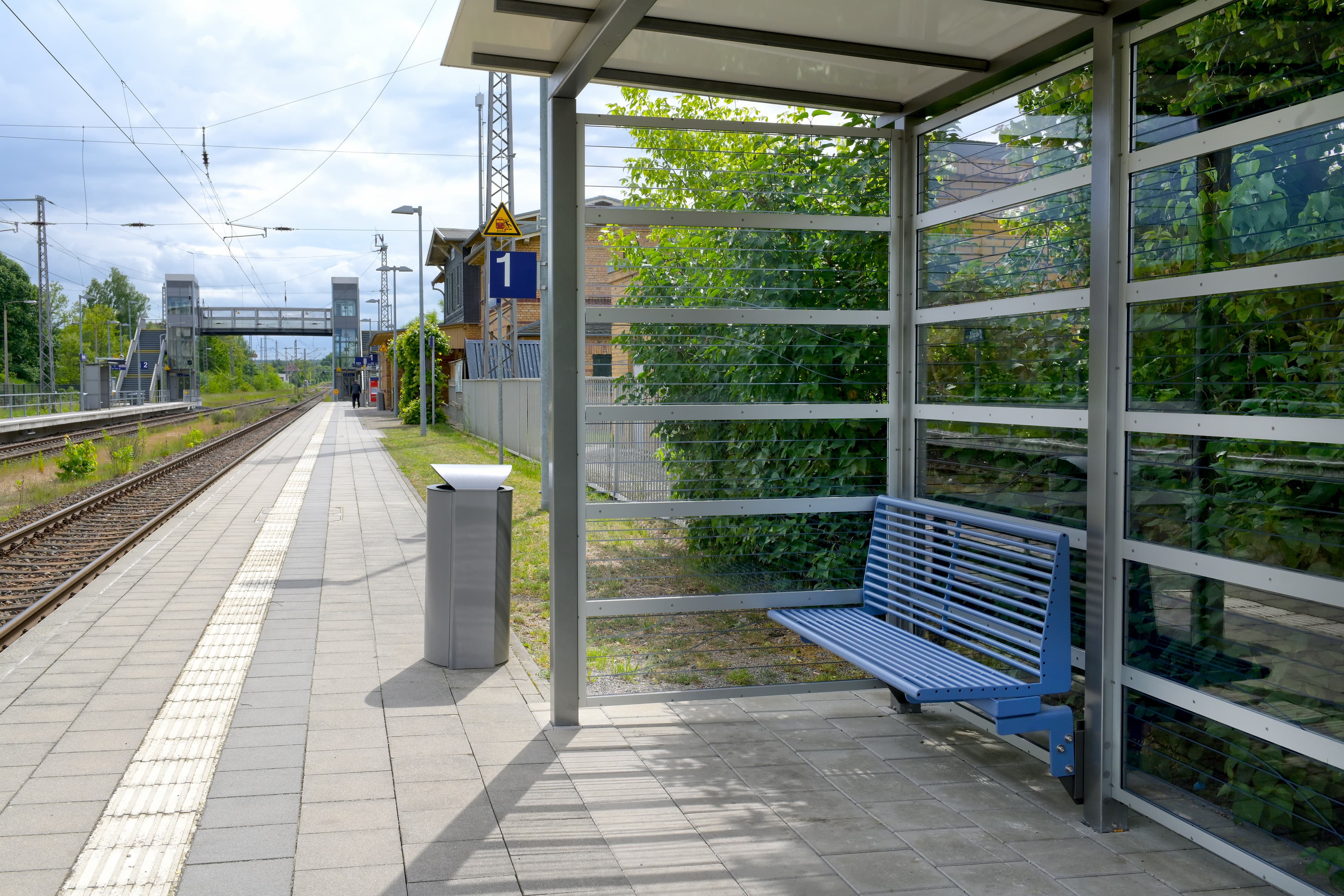 Ein Bahnsteig mit Wetterschutzhaus und Sitzbank.