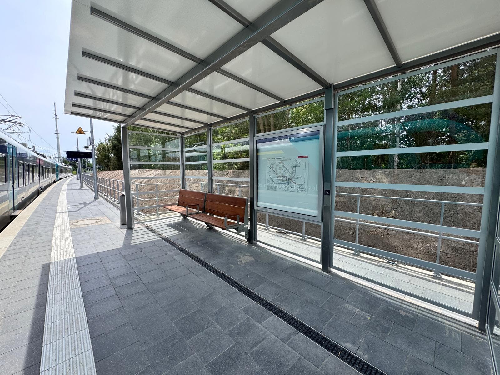 Ein vollverglastes Wetterschutzhäuschen mit Bank und Vitrine.