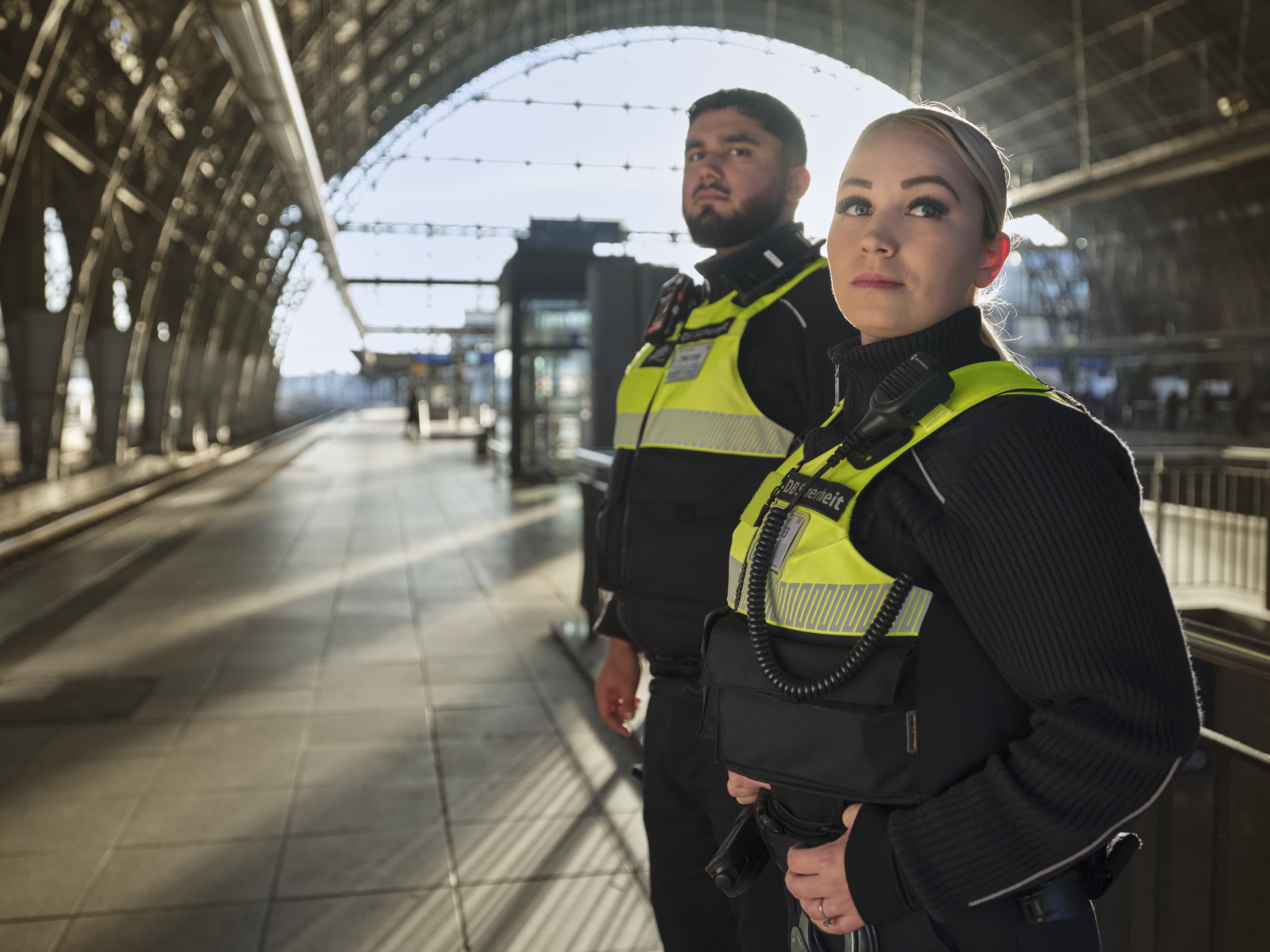 Eine Frau und ein Mann der DB Sicherheit in einer Bahnsteighalle.