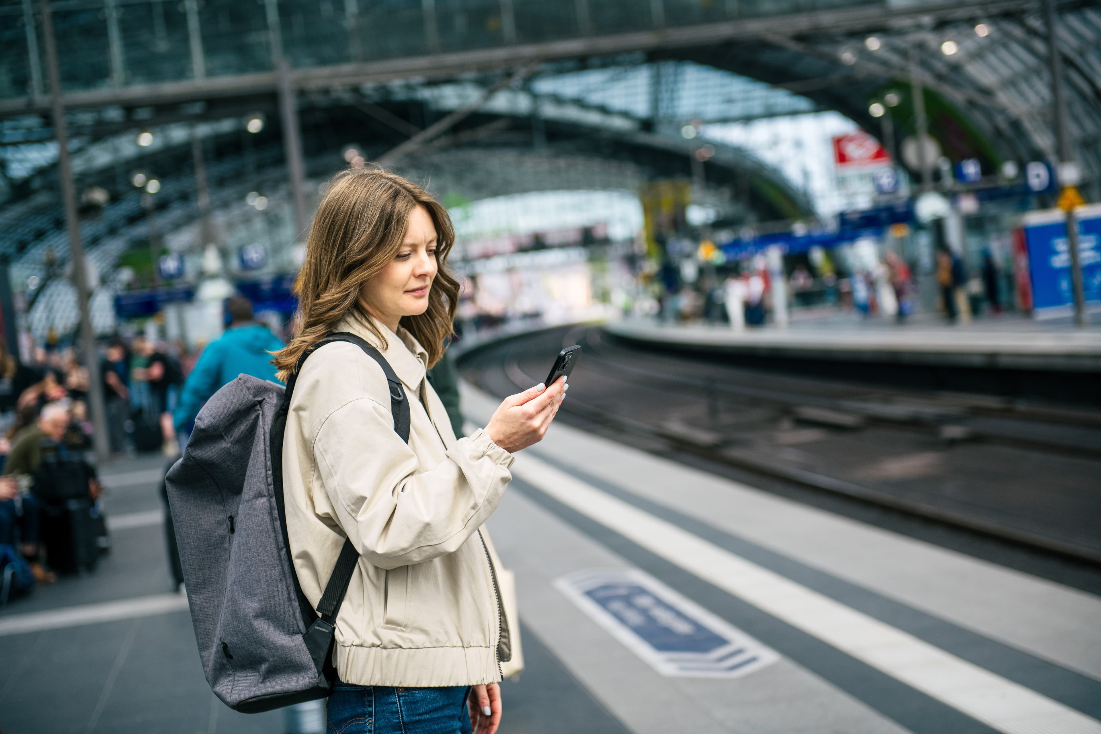 Travellers with smartphones on a platform at Berlin Central Station.