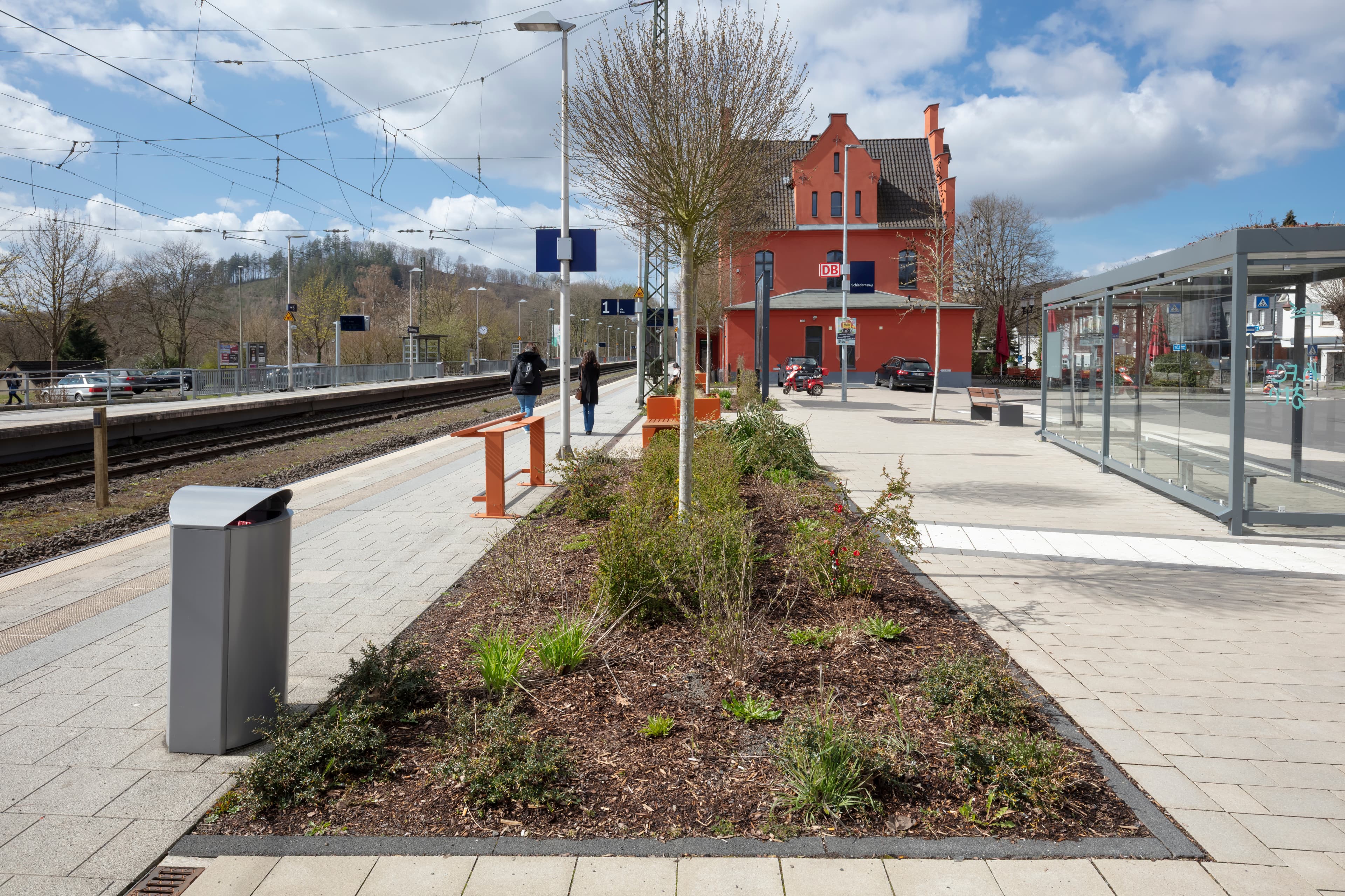 Begrünung am Bahnsteig. Rechts Wetterschutzhäuschen. Links das Gleis.