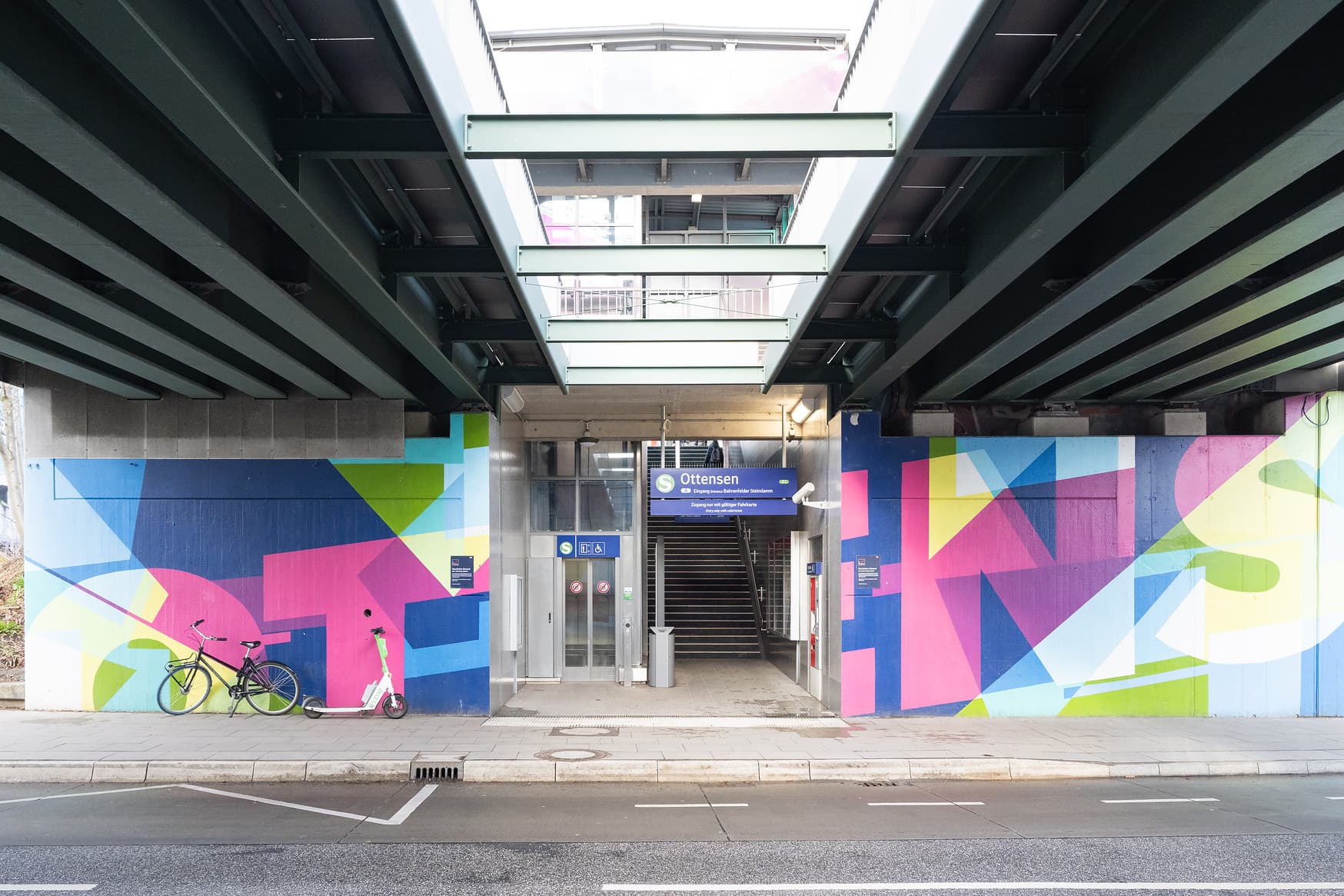 Blick auf einen Bahnsteigzugang des Bahnhofs Ottensen. Rechts und Links bunt gestaltete Wände neben dem Eingang.
