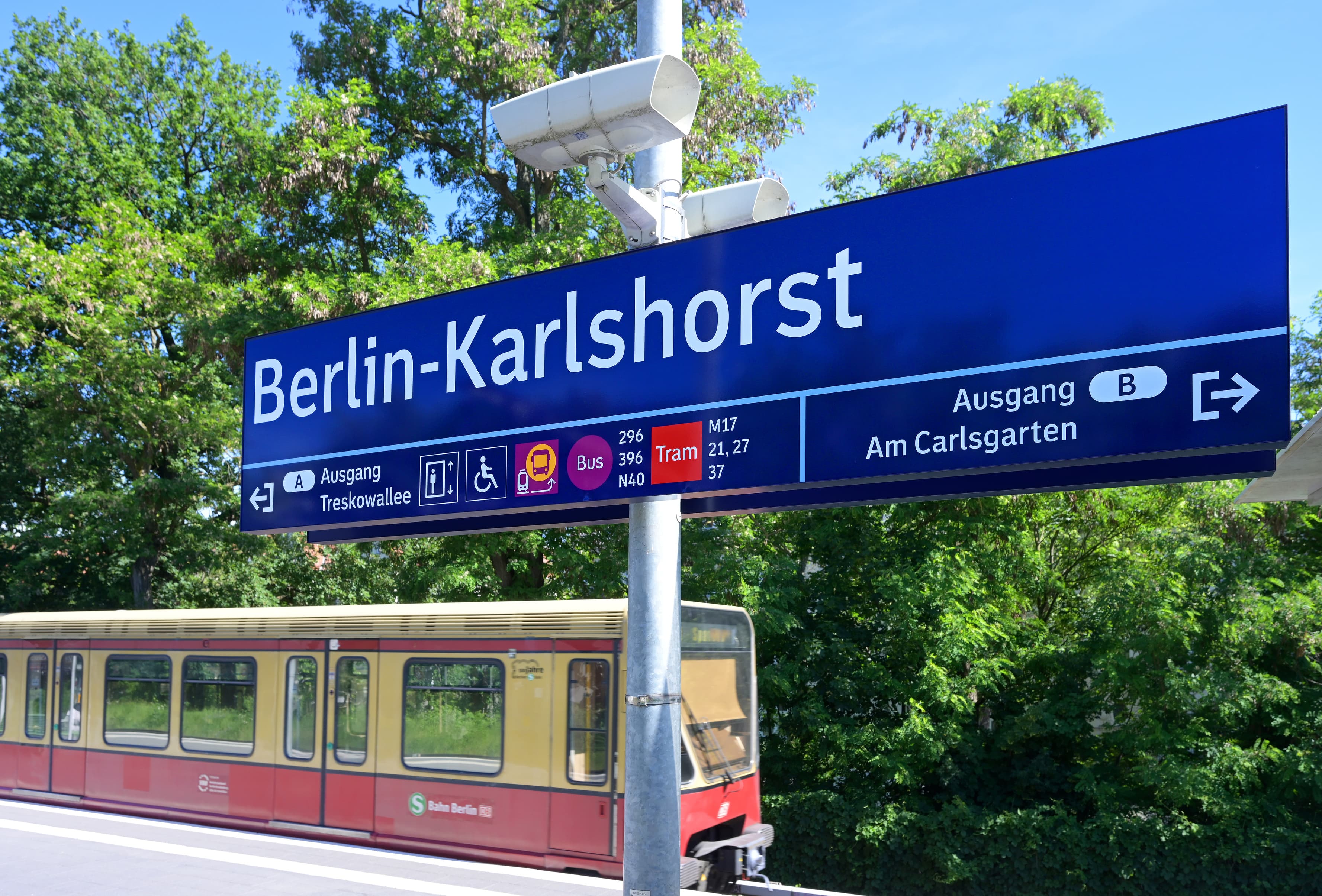 Bahnhofsschild mit S-Bahn im Hintergrund